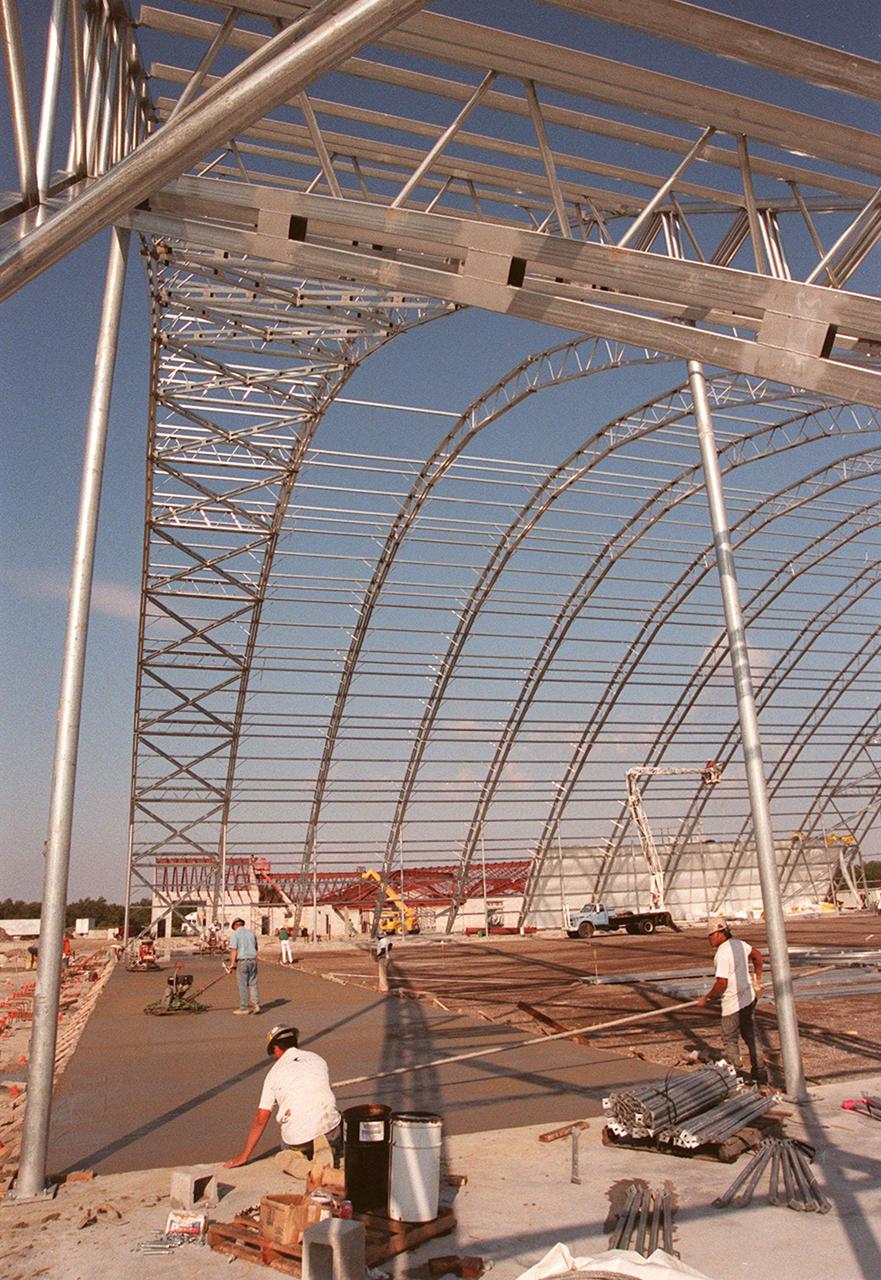 Work continues on construction of the multi-purpose hangar at the site of the $8 million Reusable Launch Vehicle (RLV) Support Complex at Kennedy Space Center. In the background can be seen the new construction for the building that will house related ground support equipment and administrative/technical support. The RLV complex will be available to accommodate the Space Shuttle; the X-34 RLV technology demonstrator; the L-1011 carrier aircraft for Pegasus and X-34; and other RLV and X-vehicle programs. The complex is jointly funded by the Spaceport Florida Authority, NASA's Space Shuttle Program and KSC. The facility will be operational in early 2000