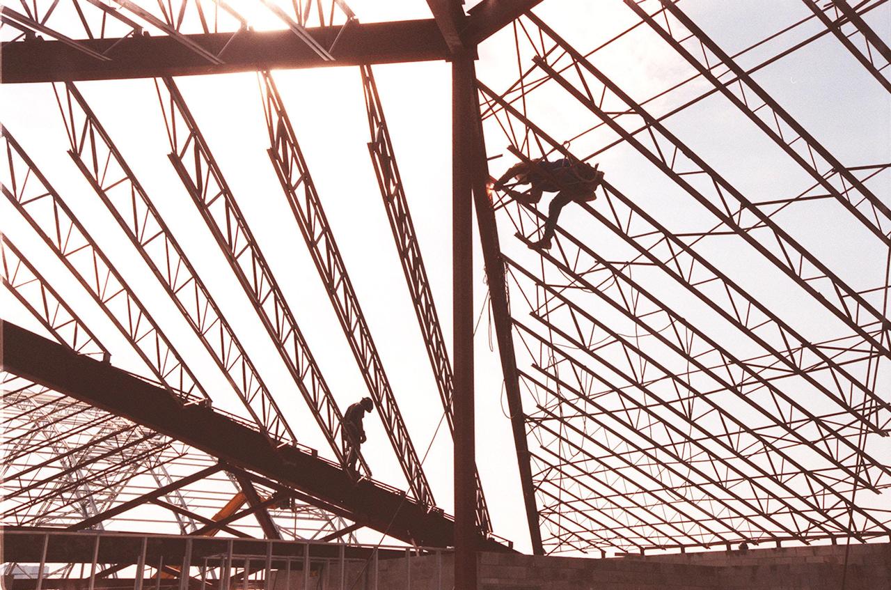 Construction workers are silhouetted against the sky as they work on the girders of a support building, part of the new $8 million Reusable Launch Vehicle (RLV) Support Complex at Kennedy Space Center. The building is to be used for related ground support equipment and administrative/technical support. The RLV complex also includes a multi-purpose hangar. The complex will be available to accommodate the Space Shuttle; the X-34 RLV technology demonstrator; the L-1011 carrier aircraft for Pegasus and X-34; and other RLV and X-vehicle programs. The facility, jointly funded by the Spaceport Florida Authority, NASA's Space Shuttle Program and KSC, will be operational in early 2000