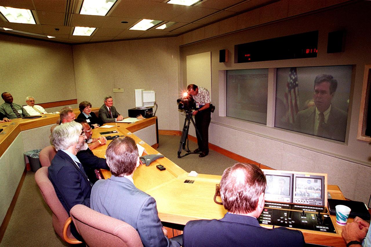 In the videoconference room at Headquarters, key representatives of KSC contractors, along with KSC directorates, fill the room during an early morning phone call from Florida Governor Jeb Bush (seen on the video screen) in Tallahassee, Fla. The call is to inaugurate the change of KSC's area code from 407 to 321, effective today. Deputy Director for Business Operations Jim Jennings (fourth from right) received the call. Next to Jennings (at his right) is seated Robert Osband, Florida Space Institute, who suggested the 3-2-1 sequence to reflect the importance of the space industry to Florida's space coast
