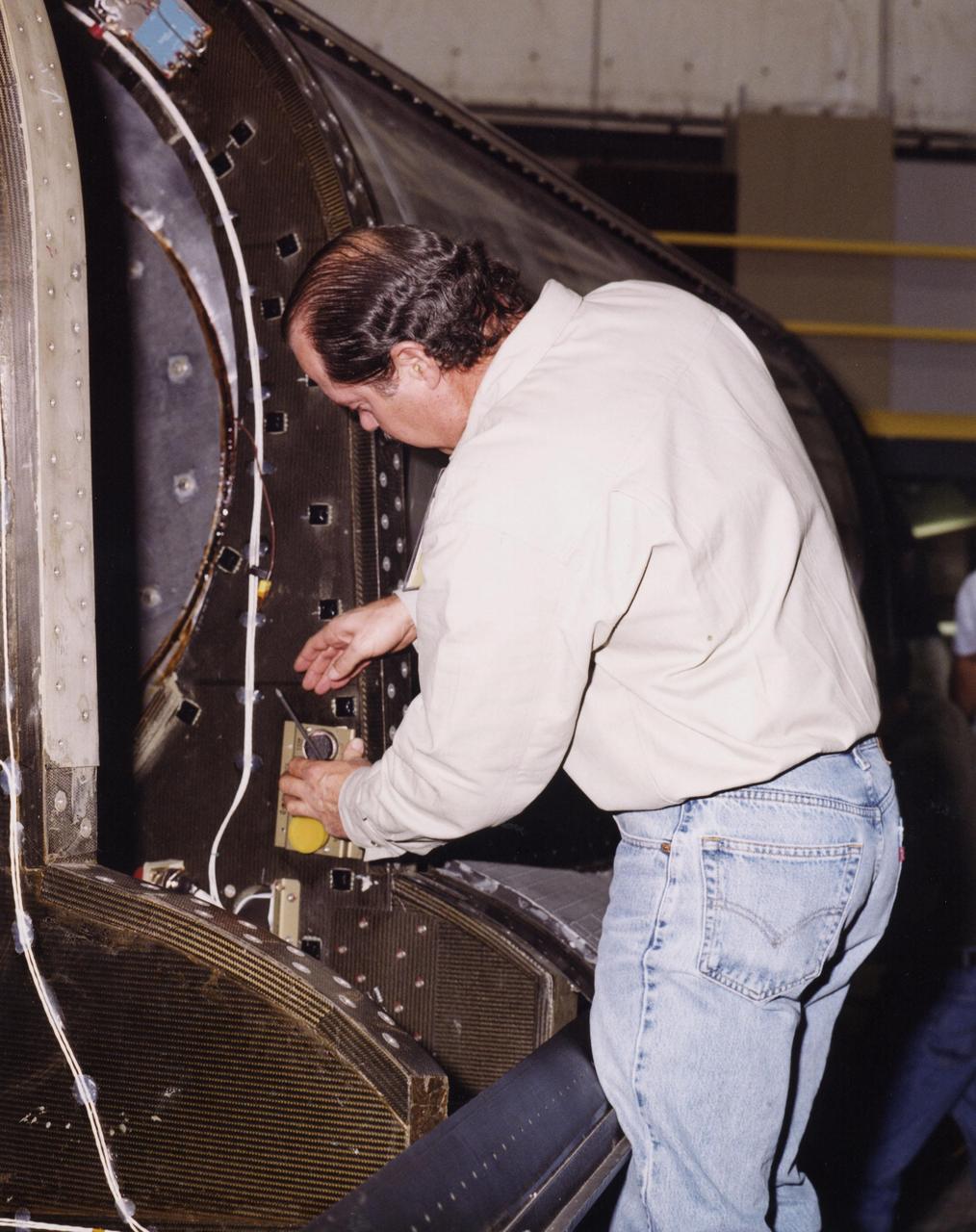 At Dryden Flight Research Center, Calif., KSC technician Bryan Taylor makes an adjustment on the modified X-34, known as A-1A. Taylor is one of eight NASA engineering technicians from KSC's Engineering Prototype Lab who have assisted Orbital Sciences Corporation and Dryden in the complex process of converting the X-34 A-1 vehicle from captive carry status to unpowered flight status, the A-1A. The other KSC technicians are Kevin Boughner, Roger Cartier, Mike Dininny, Mike Lane, Jerry Moscoso, James Niehoff Jr. and David Rowell. The X-34 is 58.3 feet long, 27.7 feet wide from wing tip to wing tip, and 11.5 feet tall from the bottom of the fuselage to the top of the tail. The autonomously operated technology demonstrator will be air-launched from an L-1011 airplane and should be capable of flying eight times the speed of sound, reaching an altitude of 250,000 feet. The X-34 Project is managed by NASA's Marshall Space Flight Center in Huntsville, Ala