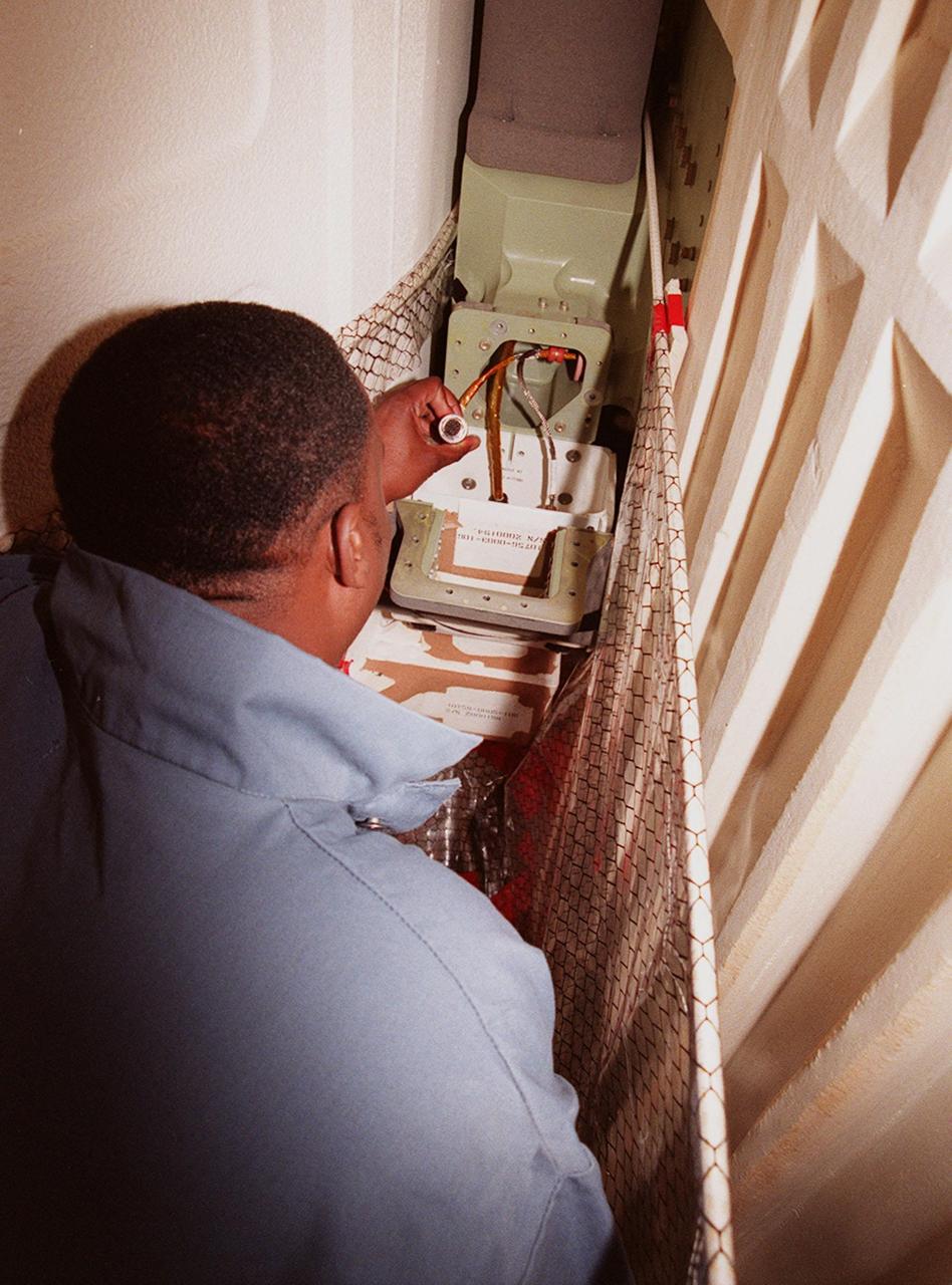 KENNEDY SPACE CENTER, FLA. -- Rodney Wilson, with United Space Alliance, inspects the range safety cable between the external tank and solid rocket boosters (SRB) on Space Shuttle Discovery. The cable, which relays a redundant emergency destruction signal between the SRBs in the unlikely event of a contingency, was damaged during close-out operations and is being replaced. Discovery's processing schedule leads to a target launch date of Dec. 6