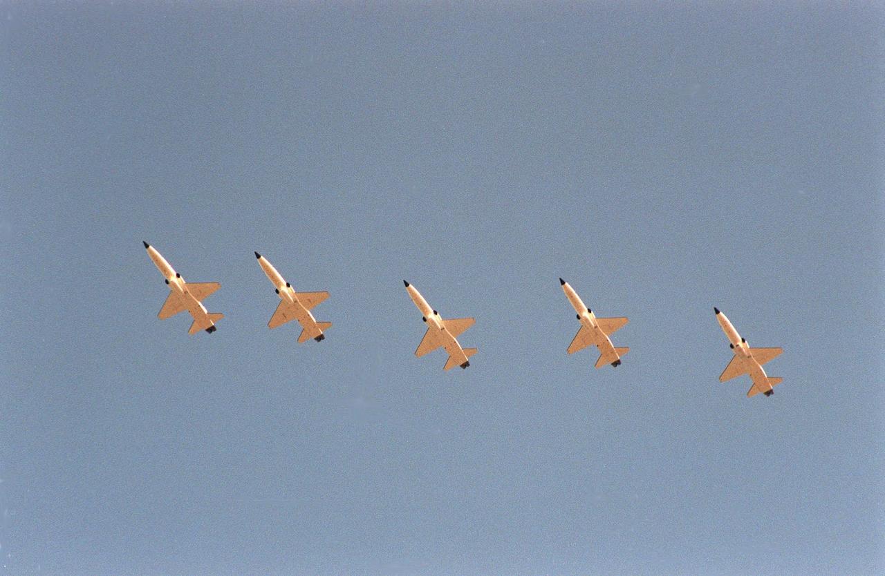 T-38 trainer jets carrying the STS-103 crew arrive in formation above Kennedy Space Center's Shuttle Landing Facility. The crew is here to take part in Terminal Countdown Demonstration Test activities this week. The TCDT provides the crew with emergency egress training, opportunities to inspect their mission payloads in the orbiter's payload bay, and simulated countdown exercises. Participating are Commander Curtis L. Brown Jr., Pilot Scott J. Kelly, and Mission Specialists Steven L. Smith, C. Michael Foale (Ph.D.), John M. Grunsfeld (Ph.D.), Claude Nicollier of Switzerland, with the European Space Agency, and Jean-François Clervoy of France, also with the European Space Agency. The mission, to service the Hubble Space Telescope, is targeted for launch Dec. 6 at 2:37 a.m. EST aboard Space Shuttle Discovery