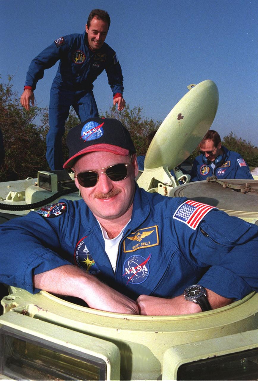 STS-103 Pilot Scott J. Kelly is ready to take his turn at driving a small armored personnel carrier that is part of emergency egress training during Terminal Countdown Demonstration Test (TCDT) activities. Behind him (left) is Mission Specialist Jean-François Clervoy of France, who is with the European Space Agency. At right is Mission Specialist Steven L. Smith. The tracked vehicle could be used by the crew in the event of an emergency at the pad during which the crew must make a quick exit from the area. The TCDT also provides simulated countdown exercises and opportunities to inspect the mission payloads in the orbiter's payload bay. STS-103 is a "call-up" mission due to the need to replace and repair portions of the Hubble Space Telescope. Four EVA's are planned to make the necessary repairs and replacements on the telescope. The other STS-103 crew members are Commander Curtis L. Brown Jr. and Mission Specialists C. Michael Foale (Ph.D.), John M. Grunsfeld (Ph.D.), plus Claude Nicollier of Switzerland, who also is with the European Space Agency. The mission is targeted for launch Dec. 6 at 2:37 a.m. EST