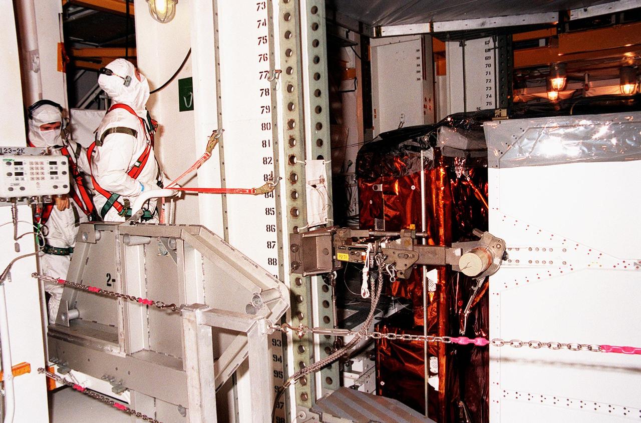 KENNEDY SPACE CENTER, FLA. -- Workers oversee the transfer of STS-103's Hubble servicing cargo from the payload changeout room at Launch Pad 39B to the payload bay in Space Shuttle Discovery. STS-103 is a "call-up" mission due to the need to replace and repair portions of the Hubble Space Telescope, including the gyroscopes that allow the telescope to point at stars, galaxies and planets. The STS-103 crew will be replacing a Fine Guidance Sensor, an older computer with a new enhanced model, an older data tape recorder with a solid-state digital recorder, a failed spare transmitter with a new one, and degraded insulation on the telescope with new thermal insulation. The crew will also install a Battery Voltage/Temperature Improvement Kit to protect the spacecraft batteries from overcharging and overheating when the telescope goes into a safe mode. Four EVA's are planned to make the necessary repairs and replacements on the telescope. The mission is targeted for launch Dec. 6 at 2:37 a.m. EST