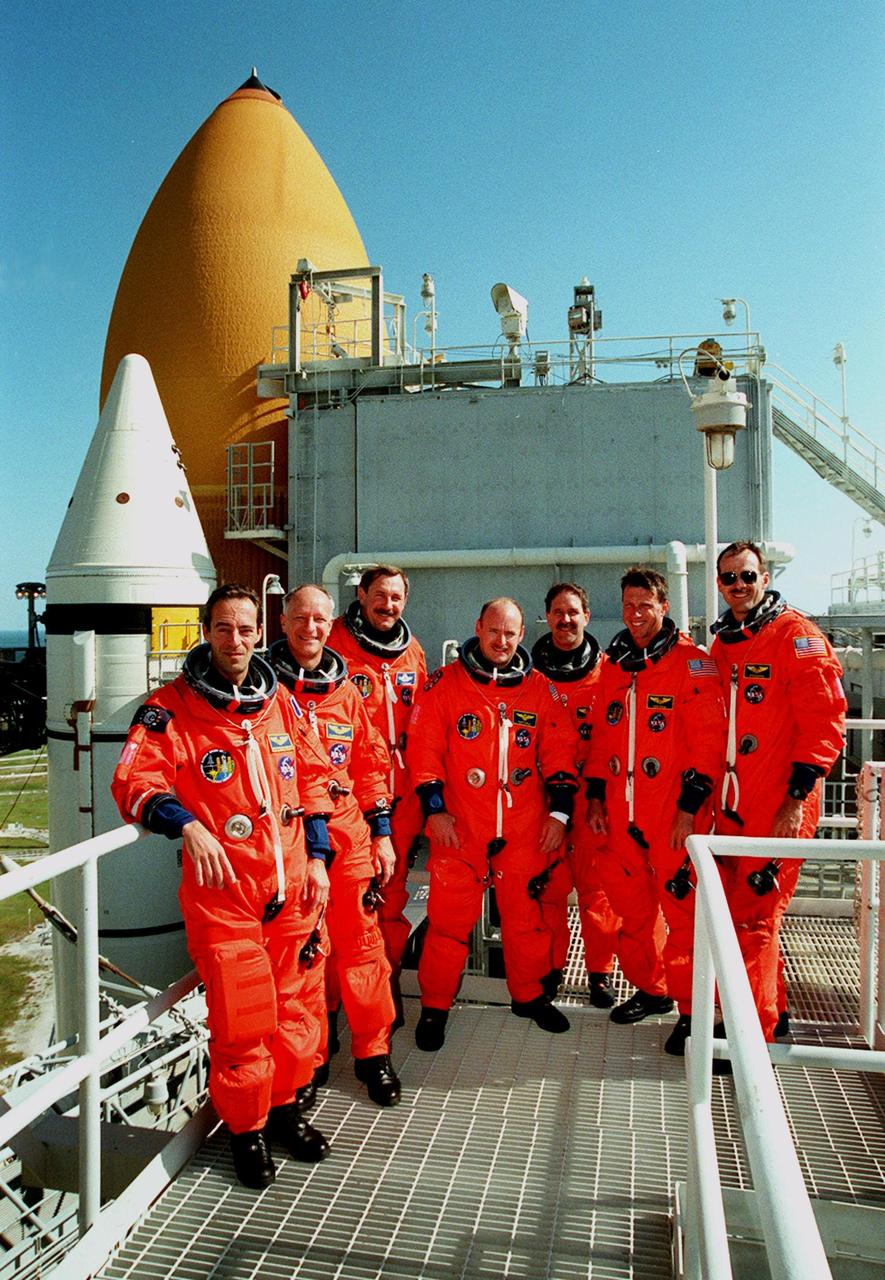 Taking a break during emergency egress training at Launch Pad 39B are (left to right) STS-103 Mission Specialists Jean-François Clervoy of France, Claude Nicollier of Switzerland, Commander Curtis L. Brown Jr., Pilot Scott J. Kelly, and Mission Specialists John M. Grunsfeld (Ph.D.), C. Michael Foale (Ph.D.) and Steven L. Smith. Clervoy and Nicollier are with the European Space Agency. The training is part of Terminal Countdown Demonstration Test (TCDT) activities that also include opportunities to inspect the mission payloads in the orbiter's payload bay and simulated countdown exercises. STS-103 is a "call-up" mission due to the need to replace and repair portions of the Hubble Space Telescope, including the gyroscopes that allow the telescope to point at stars, galaxies and planets. The STS-103 crew will be replacing a Fine Guidance Sensor, an older computer with a new enhanced model, an older data tape recorder with a solid-state digital recorder, a failed spare transmitter with a new one, and degraded insulation on the telescope with new thermal insulation. The crew will also install a Battery Voltage/Temperature Improvement Kit to protect the spacecraft batteries from overcharging and overheating when the telescope goes into a safe mode. Four EVA's are planned to make the necessary repairs and replacements on the telescope. The mission is targeted for launch Dec. 6 at 2:37 a.m. EST