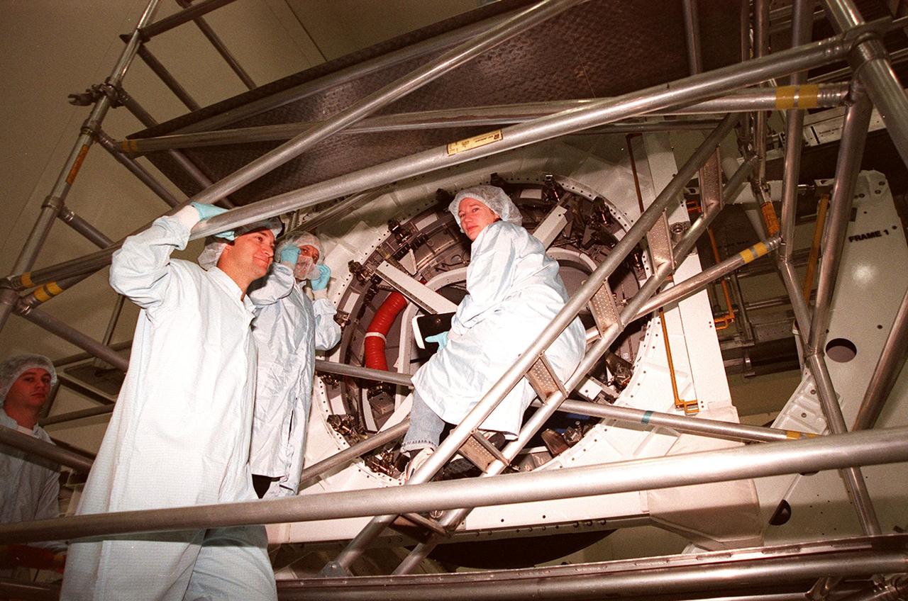 KENNEDY SPACE CENTER, FLA. -- Looking over a Pressurized Mating Adapter (PMA-3) in the Space Station Processing Facility are Arne Aamodt, with Johnson Space Center, Yuriy Vladimirovich Usachev and Susan J. Helms. Usachev and Helms are two members of the STS-102 crew, who will be staying on the International Space Station (ISS). The third crew member is James S. Voss. They have been designated the Expedition II crew. Mission STS-102 also will be carrying the Leonardo Multi-Purpose Logistics Module (MPLM) to the ISS. The Leonardo will be filled with equipment and supplies to outfit the U.S. laboratory module, which will have been carried to the ISS on a preceding Shuttle flight. In order to function as an attached station module as well as a cargo transport, logistics modules (there are three) also include components that provide some life support, fire detection and suppression, electrical distribution and computer functions. Eventually, the modules also will carry refrigerator freezers for transporting experiment samples and food to and from the station. On the return of STS-102 to Earth, it will bring back the first crew on the station: Bill Shepherd, Sergei Krikalev and Yuri Gidzenko. STS-102 is scheduled to launch no earlier than Oct. 19, 2000, from Launch Pad 39A, Kennedy Space Center