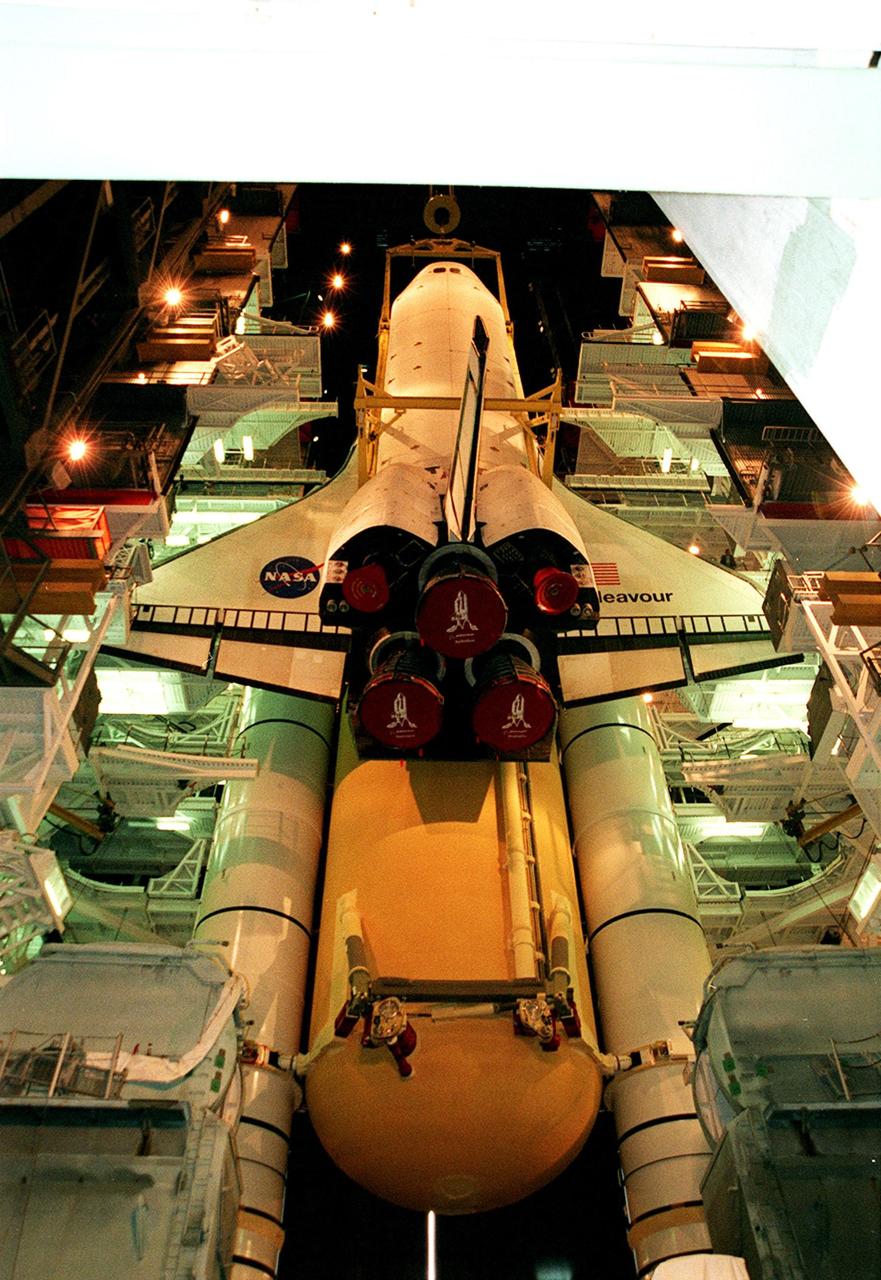 KENNEDY SPACE CENTER, FLA. -- Viewed from the ground level in high bay 1 of the VAB, the orbiter Endeavour seems to float in mid-air as it is lowered for mating with the external tank and solid rocket boosters behind and below it. Space Shuttle Endeavour is targeted for launch on mission STS-99 Jan. 13, 2000, at 1:11 p.m. EST. STS-99 is the Shuttle Radar Topography Mission, an international project spearheaded by the National Imagery and Mapping Agency and NASA, with participation of the German Aerospace Center DLR. The SRTM consists of a specially modified radar system that will gather data for the most accurate and complete topographic map of the Earth's surface that has ever been assembled. SRTM will make use of radar interferometry, wherein two radar images are taken from slightly different locations. Differences between these images allow for the calculation of surface elevation, or change. The SRTM hardware will consist of one radar antenna in the shuttle payload bay and a second radar antenna attached to the end of a mast extended 60 meters (195 feet) out from the shuttle