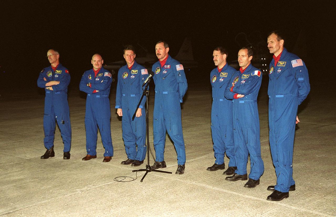 The STS-103 crew greets the media at the Shuttle Landing Facility after arriving aboard T-38 jets to make final preparations for their launch. From left, they are Mission Specialist Claude Nicollier of Switzerland, Pilot Scott J. Kelly, Mission Specialist C. Michael Foale (Ph.D.), Commander Curtis L. Brown Jr. (at microphone), and Mission Specialists John M. Grunsfeld (Ph.D.), Jean-François Clervoy of France, and Steven L. Smith. Nicollier and Clervoy both represent the European Space Agency. The STS-103 mission, to service the Hubble Space Telescope a third time, is scheduled for launch Dec. 11 at 12:13 a.m. EST from Launch Pad 39B