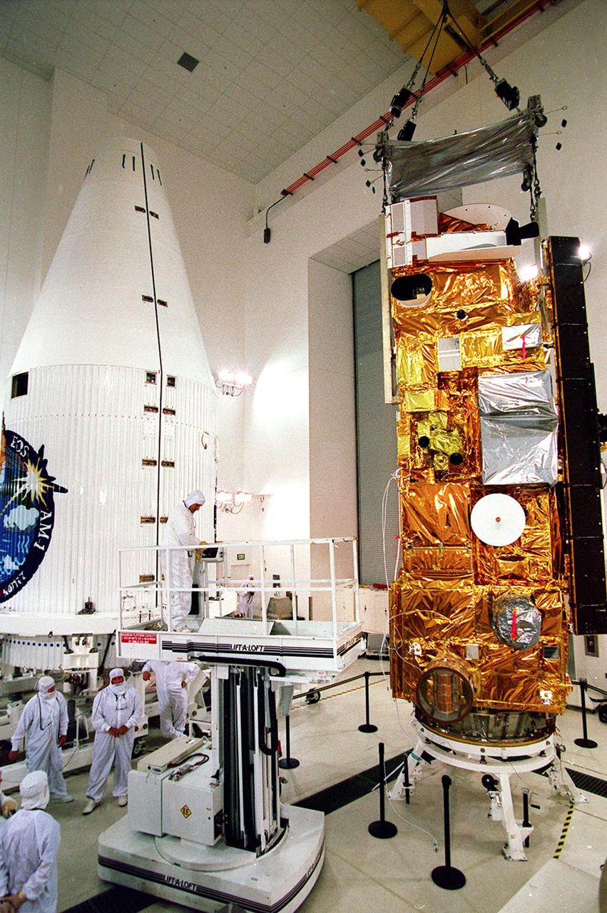 Workers (left) at Vandenberg AFB, Calif., get ready to prepare NASA's Terra spacecraft (right) for encapsulation in the rocket faring (left) before launch. The spacecraft is expected to be launched Dec. 16 aboard a Lockheed Martin Atlas IIAS rocket from the AFB's Space Launch Complex 3 East. Terra comprises five state-of-the-art sets of instruments that will collect data for continuous, long-term records of the state of Earth's land, oceans and atmosphere. Together with data from other satellite systems launched by NASA and other countries, Terra will inaugurate a new self-consistent data record that will be gathered over the next 15 years. From an altitude of 438 miles, Terra will circle the Earth 16 times a day from pole to pole (98 degree inclination), crossing the equator at 10:30 a.m. The five Terra instruments will operate by measuring sunlight reflected by the Earth and heat emitted by the Earth
