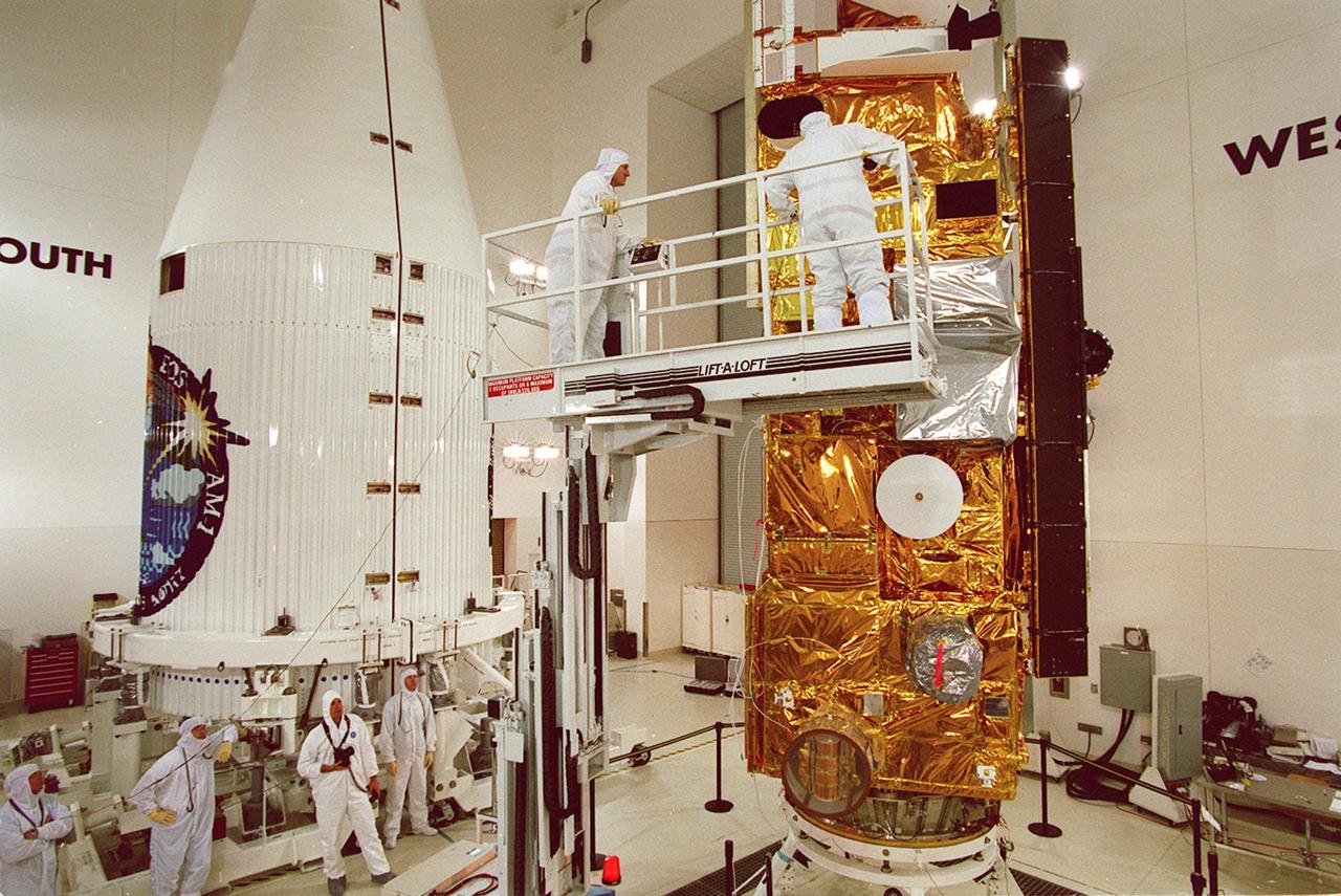 Workers at Vandenberg AFB, Calif., help prepare NASA's Terra spacecraft (right) for encapsulation in the rocket faring (left). Terra is expected to be launched aboard a Lockheed Martin Atlas IIAS rocket Dec. 16 from Space Launch Complex 3 East at Vandenberg. Terra comprises five state-of-the-art sets of instruments that will collect data for continuous, long-term records of the state of Earth's land, oceans and atmosphere. Together with data from other satellite systems launched by NASA and other countries, Terra will inaugurate a new self-consistent data record that will be gathered over the next 15 years. From an altitude of 438 miles, Terra will circle the Earth 16 times a day from pole to pole (98 degree inclination), crossing the equator at 10:30 a.m. The five Terra instruments will operate by measuring sunlight reflected by the Earth and heat emitted by the Earth
