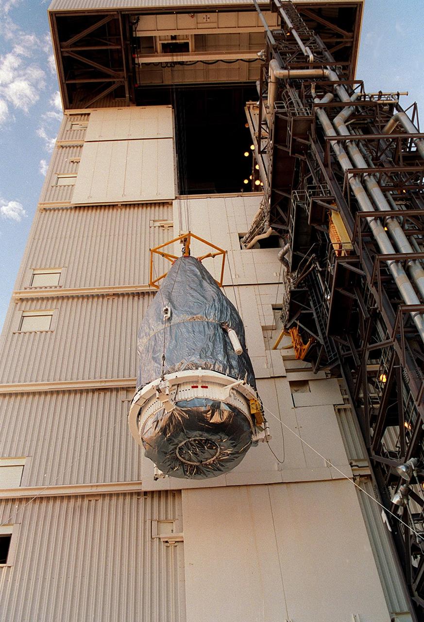 The rocket faring is lifted up the launch tower for mating with the Lockheed Martin Atlas IIAS rocket after encapsulation of Terra, formerly EOS AM-1. It is scheduled for launch Dec. 16 from Space Launch Complex 3 East at Vandenberg AFB, Calif. Terra comprises five state-of-the-art sets of instruments that will collect data for continuous, long-term records of the state of Earth's land, oceans and atmosphere. Together with data from other satellite systems launched by NASA and other countries, it will inaugurate a new self-consistent data record that will be gathered over the next 15 years. From an altitude of 438 miles, Terra will circle the Earth 16 times a day from pole to pole (98 degree inclination), crossing the equator at 10:30 a.m. The five Terra instruments will operate by measuring sunlight reflected by the Earth and heat emitted by the Earth
