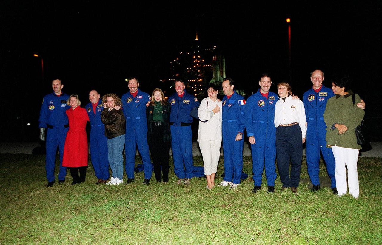 The STS-103 crew pose for photographers with their loved ones at Launch Pad 39B. Space Shuttle Discovery is in the background, next to the Fixed Service Structure lit up like a Christmas tree. Viewed left to right are Mission Specialist Steven L. Smith and his wife, Peggy; Pilot Scott J. Kelly and his wife, Leslie; Commander Curtis L. Brown Jr. and his fiancee, Ann Brickert; Mission Specialist C. Michael Foale; Laurence Clervoy and her husband, Mission Specialist Jean-François Clervoy; Mission Specialist John M. Grunsfeld and his wife, Carol; Mission Specialist Claude Nicollier and his wife, Susana. Nicollier and Clervoy are with the European Space Agency. The mission, to service the Hubble Space Telescope, is scheduled for launch Dec. 17 at 8:47 p.m. EST from Launch Pad 39B. Mission objectives include replacing gyroscopes and an old computer, installing another solid state recorder, and replacing damaged insulation in the telescope. The mission is expected to last about 8 days and 21 hours. Discovery is expected to land at KSC Sunday, Dec. 26, at about 6:25 p.m. EST