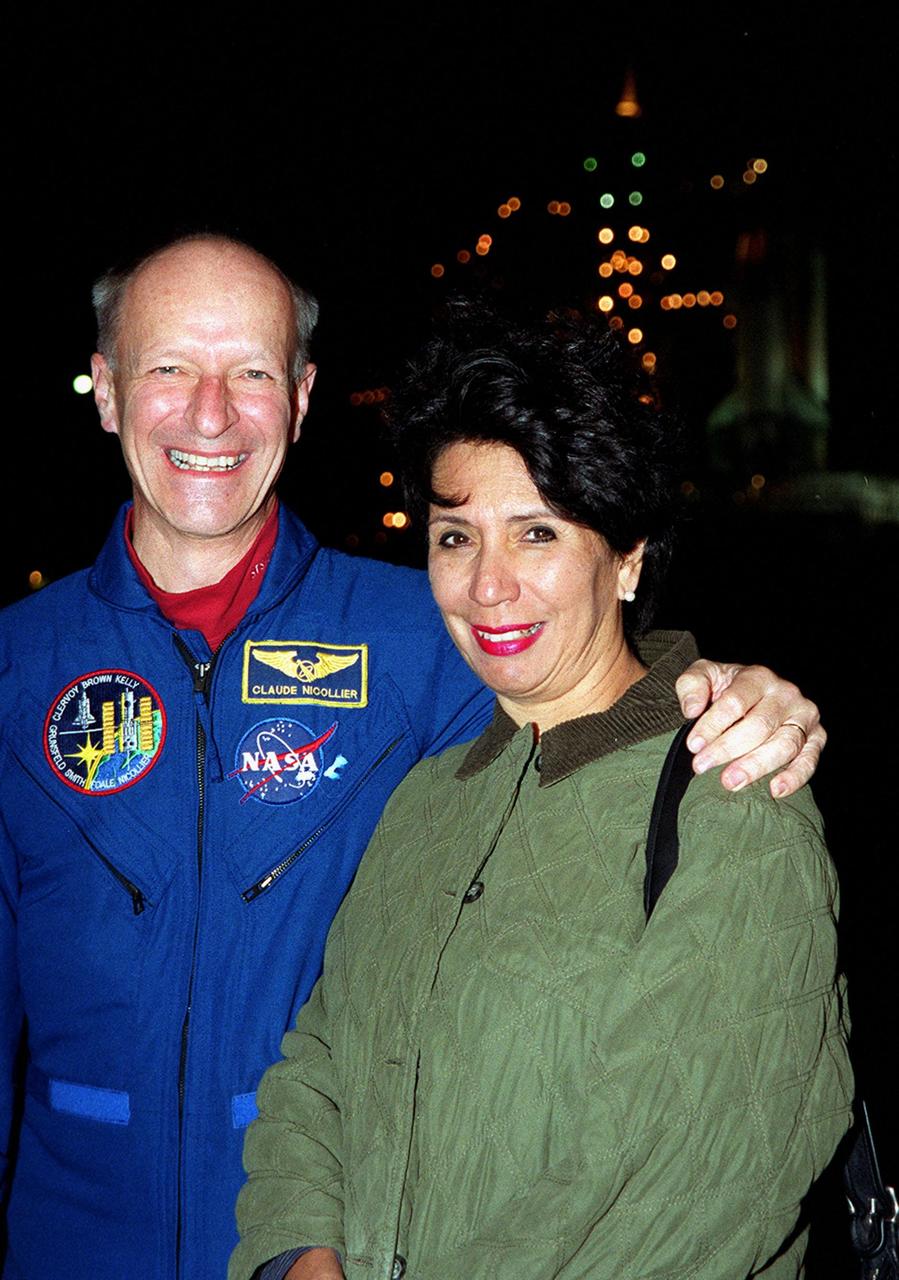 STS-103 Mission Specialist Claude Nicollier of Switzerland and his wife, Susana, pose at Launch Pad 39B during a meeting of the STS-103 crew with their family and friends. Nicollier is with the European Space Agency. The lights in the background are on the Fixed Service Structure next to Space Shuttle Discovery. The mission, to service the Hubble Space Telescope, is scheduled for launch Dec. 17 at 8:47 p.m. EST from Launch Pad 39B. Mission objectives include replacing gyroscopes and an old computer, installing another solid state recorder, and replacing damaged insulation in the telescope. The mission is expected to last about 8 days and 21 hours. Discovery is expected to land at KSC Sunday, Dec. 26, at about 6:25 p.m. EST