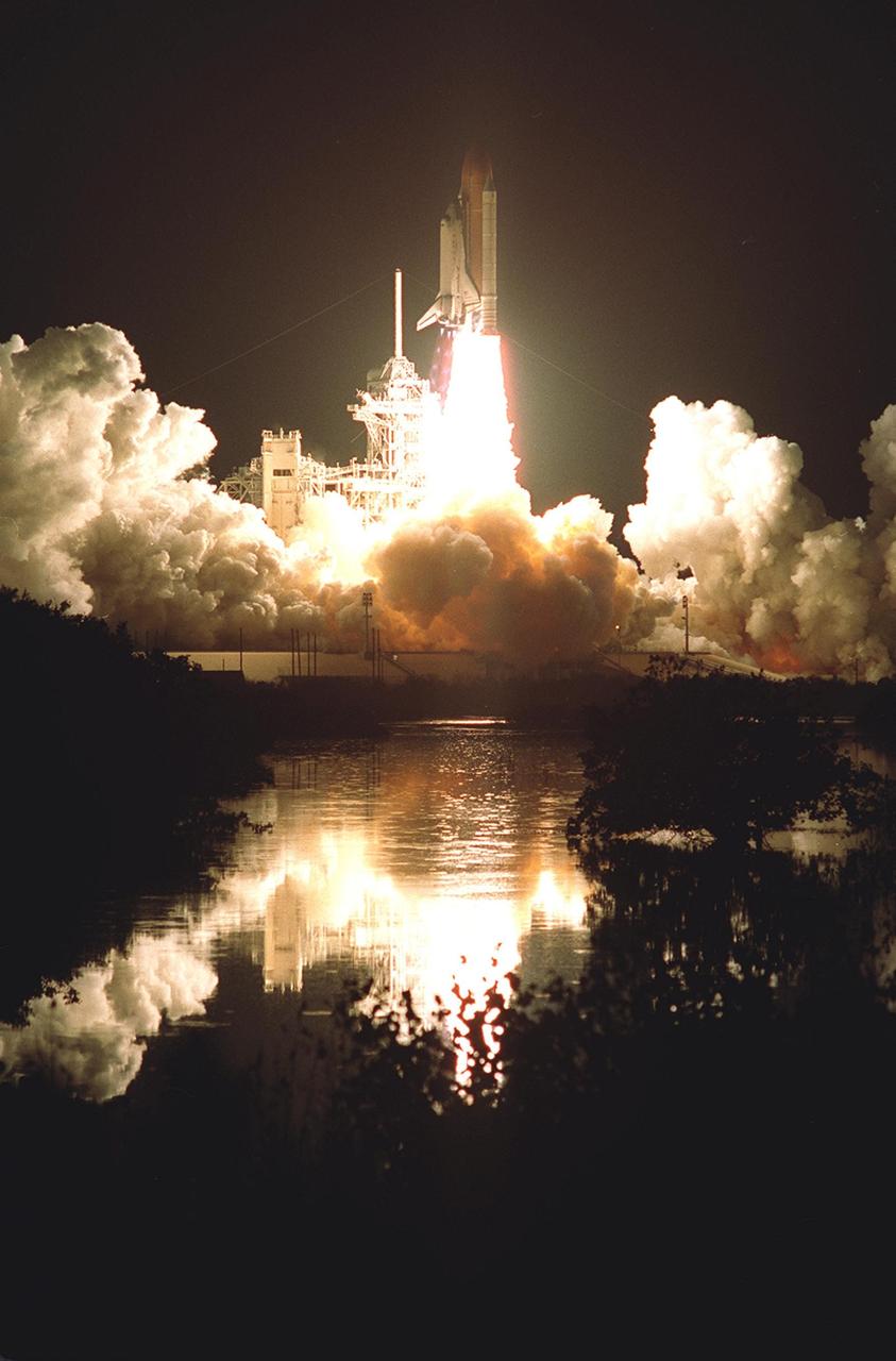 Turning night into day, the brilliance of Space Shuttle Discovery's launch is reflected in the waters nearby. Liftoff occurred at 7:50 p.m. EST from Launch Pad 39B. On board are Commander Curtis L. Brown Jr., Pilot Scott J. Kelly and Mission Specialists Steven L. Smith, C. Michael Foale (Ph.D.), John M. Grunsfeld (Ph.D.), Claude Nicollier of Switzerland and Jean-François Clervoy of France. Nicollier and Clervoy are with the European Space Agency. STS-103 is a Hubble Servicing Mission, with three planned space walks designed to install new equipment and replace old. The primary objective is to replace the gyroscopes that make up the three Rate Sensor Units. Extravehicular activities include installing a new computer, changing out one of the Fine Guidance Sensors, replacing a tape recorder with a new solid state recorder, and installing a voltage/temperature improvement kit, and begin repairing the insulation on the telescope's outer surface. After the 7-day, 21-hour mission, Discovery is expected to land at KSC Monday, Dec. 27, at about 5:24 p.m. EST. This is the 27th flight of Discovery and the 96th mission in the Space Shuttle Program. It is the third launch at Kennedy Space Center in 1999