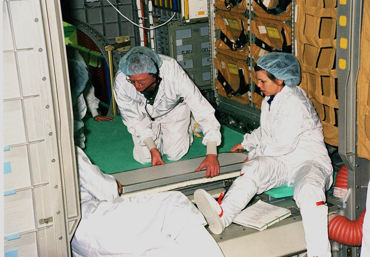 KENNEDY SPACE CENTER, FLA. -- During a Crew Equipment Interface Test (CEIT) at SPACEHAB, in Titusville, Fla., STS-101 crew members check out the SPACEHAB Logistics Double Module that will be part of the payload for their mission. At right is Mission Specialist Mary Ellen Weber (Ph.D.), who is assisted by a SPACEHAB worker. Other crew members taking part in the CEIT are Commander James Donald Halsell Jr., Pilot Scott J. "Doc" Horowitz (Ph.D.), and Mission Specialists Edward Tsang Lu (Ph.D.), Jeffrey N. Williams, and Yuri Malenchenko and Boris W. Morukov, who are with the Russian Space Agency. The primary objective of the STS-101 mission is to complete the initial outfitting of the International Space Station, making it fully ready for the first long-term crew. The seven-member crew will transfer almost two tons of equipment and supplies from SPACEHAB. Additionally, they will unpack a shipment of supplies delivered earlier by a Russian Progress space tug and begin outfitting the newly arrived Zvezda Service Module. Three astronauts will perform two space walks to transfer and install parts of the Russian Strela cargo boom that are attached to SPACEHAB's Integrated Cargo Container, connect utility cables between Zarya and Zvezda, and install a magnetometer/pole assembly on the Service Module. Additional activities for the STS-101 astronauts include working with the Space Experiment Module (SEM-06) and the Mission to America's Remarkable Schools (MARS), two educational initiatives. STS-101 is scheduled for launch no earlier than March 16, 2000