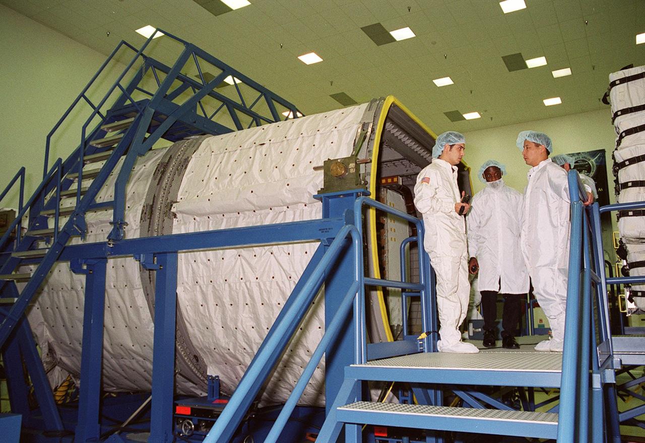 KENNEDY SPACE CENTER, FLA. -- At SPACEHAB, in Titusville, Fla., STS-101 Mission Specialists Edward Tsang Lu (Ph.D.), at right, talks with workers about the SPACEHAB Logistics Double Module at left. The module is part of the payload for the mission. Lu and other crew members Commander James Donald Halsell Jr., Pilot Scott J. "Doc" Horowitz (Ph.D.), and Mission Specialists Mary Ellen Weber (Ph.D), Jeffrey N. Williams, and Boris W. Morukov and Yuri Malenchenko , who are with the Russian Space Agency , are taking part in a Crew Equipment Interface Test. The primary objective of the STS-101 mission is to complete the initial outfitting of the International Space Station, making it fully ready for the first long-term crew. The seven-member crew will transfer almost two tons of equipment and supplies from SPACEHAB. Additionally, they will unpack a shipment of supplies delivered earlier by a Russian Progress space tug and begin outfitting the newly arrived Zvezda Service Module. Three astronauts will perform two space walks to transfer and install parts of the Russian Strela cargo boom that are attached to SPACEHAB's Integrated Cargo Container, connect utility cables between Zarya and Zvezda, and install a magnetometer/pole assembly on the Service Module. Additional activities for the STS-101 astronauts include working with the Space Experiment Module (SEM-06) and the Mission to America's Remarkable Schools (MARS), two educational initiatives. STS-101 is scheduled for launch no earlier than March 16, 2000