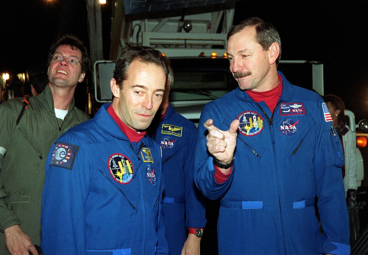 After landing at the Shuttle Landing Facility, STS-103 Mission Specialist Jean-François Clervoy of France (left), with the European Space Agency (ESA), and Commander Curtis L. Brown Jr. (right) look over the orbiter Discovery. They and other crew members Pilot Scott J. Kelly and Mission Specialists Steven L. Smith, C. Michael Foale (Ph.D.), John M. Grunsfeld (Ph.D.) and Claude Nicollier of Switzerland (also with ESA), completed a successful eight-day mission to service the Hubble Space Telescope, spending the Christmas holiday in space in order to accomplish their mission before the end of 1999. During the mission, Discovery's four space-walking astronauts, Smith, Foale, Grunsfeld and Nicollier, spent 24 hours and 33 minutes upgrading and refurbishing Hubble, making it more capable than ever to renew its observations of the universe. Mission objectives included replacing gyroscopes and an old computer, installing another solid state recorder, and replacing damaged insulation in the telescope. Hubble was released from the end of Discovery's robot arm on Christmas Day. Main gear touchdown was at 7:00:47 p.m. EST. Nose gear touchdown occurred at 7:00:58 p.m. EST and wheel stop at 7:01:34 p.m. EST. This was the 96th flight in the Space Shuttle program and the 27th for the orbiter Discovery. The landing was the 20th consecutive Shuttle landing in Florida and the 13th night landing in Shuttle program history