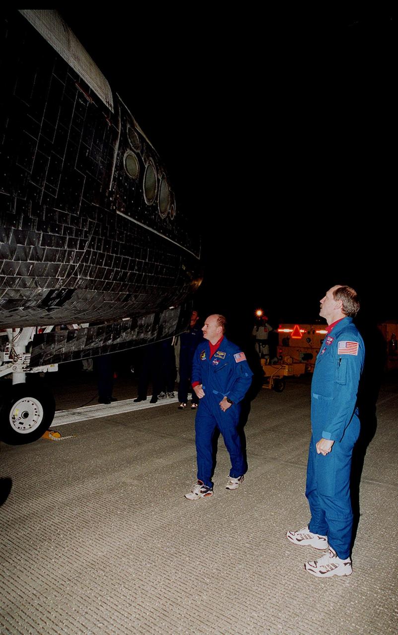 After landing at the Shuttle Landing Facility, STS-103 Pilot Scott J. Kelly (left) and Commander Curtis L. Brown Jr. (right) look at the tiles on orbiter Discovery. They and other crew members Mission Specialists Steven L. Smith, C. Michael Foale (Ph.D.), John M. Grunsfeld (Ph.D.), Jean-Francois Clervoy of France and Claude Nicollier of Switzerland, completed a successful eight-day mission to service the Hubble Space Telescope, spending the Christmas holiday in space in order to accomplish their mission before the end of 1999. During the mission, Discovery's four space-walking astronauts, Smith, Foale, Grunsfeld and Nicollier, spent 24 hours and 33 minutes upgrading and refurbishing Hubble, making it more capable than ever to renew its observations of the universe. Mission objectives included replacing gyroscopes and an old computer, installing another solid state recorder, and replacing damaged insulation in the telescope. Hubble was released from the end of Discovery's robot arm on Christmas Day. Main gear touchdown was at 7:00:47 p.m. EST. Nose gear touchdown occurred at 7:00:58 p.m. EST and wheel stop at 7:01:34 p.m. EST. This was the 96th flight in the Space Shuttle program and the 27th for the orbiter Discovery. The landing was the 20th consecutive Shuttle landing in Florida and the 13th night landing in Shuttle program history