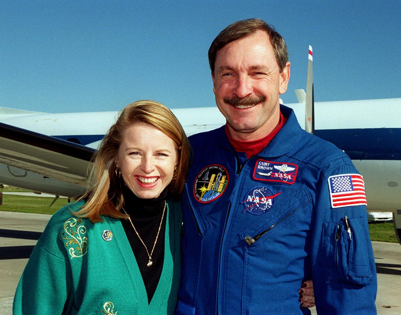STS-103 Commander Curtis L. Brown Jr. and his fiancee, Ann Brickert, smile for the camera on the runway at Patrick Air Force Base. The STS-103 crew and their families are preparing to board an airplane that will return them to their home base at the Johnson Space Center in Houston following the successful completion of their mission. Discovery landed in darkness the previous evening, Dec. 27, on runway 33 at KSC's Shuttle Landing Facility at 7:00:47 p.m. EST. This was the first time that a Shuttle crew spent the Christmas holiday in space. The other STS-103 crew members are Pilot Scott J. Kelly and Mission Specialists Steven L. Smith, C. Michael Foale (Ph.D.), John M. Grunsfeld (Ph.D.), Claude Nicollier of Switzerland and Jean-François Clervoy of France. The STS-103 mission supplied the Hubble Space Telescope with six new gyroscopes, six new voltage/temperature improvement kits, a new onboard computer, a new solid state recorder and new data transmitter, and a new fine guidance sensor along with new insulation on parts of the orbiting telescope. This was the 96th flight in the Space Shuttle program and the 27th for the orbiter Discovery
