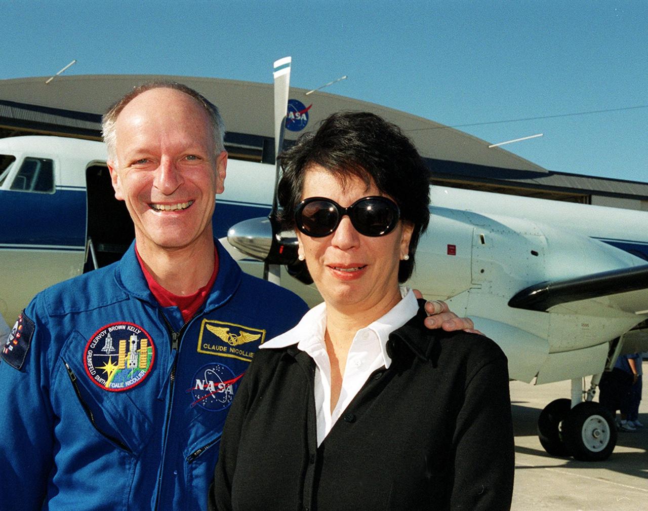 STS-103 Mission Specialist Claude Nicollier of Switzerland and his wife, Susana, beam at the camera on the runway at Patrick Air Force Base. The STS-103 crew and their families are preparing to board an airplane that will return them to their home base at the Johnson Space Center in Houston following the successful completion of their mission. Discovery landed in darkness the previous evening, Dec. 27, on runway 33 at KSC's Shuttle Landing Facility at 7:00:47 p.m. EST. This was the first time that a Shuttle crew spent the Christmas holiday in space. The other STS-103 crew members are Commander Curtis L. Brown Jr.; Pilot Scott J. Kelly; and Mission Specialists Steven L. Smith, C. Michael Foale (Ph.D.), John M. Grunsfeld (Ph.D.), and Jean-François Clervoy of France. The STS-103 mission supplied the Hubble Space Telescope with six new gyroscopes, six new voltage/temperature improvement kits, a new onboard computer, a new solid state recorder and new data transmitter, and a new fine guidance sensor along with new insulation on parts of the orbiting telescope. This was the 96th flight in the Space Shuttle program and the 27th for the orbiter Discovery