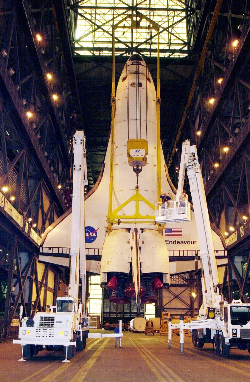 KENNEDY SPACE CENTER, FLA. -- As the orbiter Endeavour hangs suspended from a crane inside the Vehicle Assembly Building, workers make adjustments on it before it is lifted and stacked with its external tank and solid rocket boosters. The stack is in high bay 1. Space Shuttle Endeavour is scheduled to be launched Nov. 30 on mission STS-97, the sixth construction flight to the International Space Station