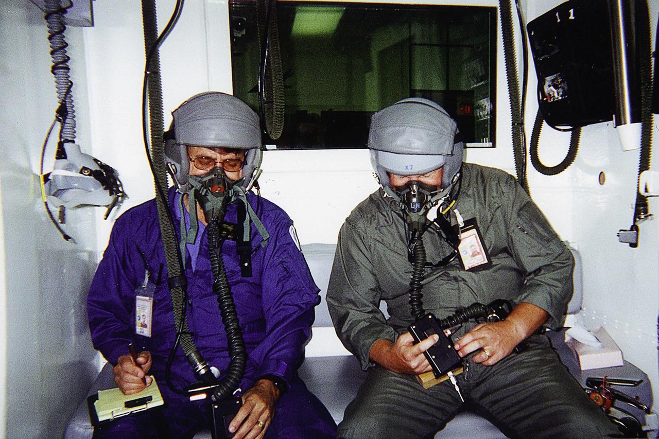 Jan Zysko (left) and Rich Mizell (right) test a Personal Cabin Pressure Altitude Monitor in an altitude chamber at Tyndall Air Force Base in Florida. Zysko invented the pager-sized monitor that alerts wearers of a potentially dangerous or deteriorating cabin pressure altitude condition, which can lead to life-threatening hypoxia. Zysko is chief of the KSC Spaceport Engineering and Technology directorate's data and electronic systems branch. Mizell is a Shuttle processing engineer. The monitor, which has drawn the interest of such organizations as the Federal Aviation Administration for use in commercial airliners and private aircraft, was originally designed to offer Space Shuttle and Space Station crew members added independent notification about any depressurization