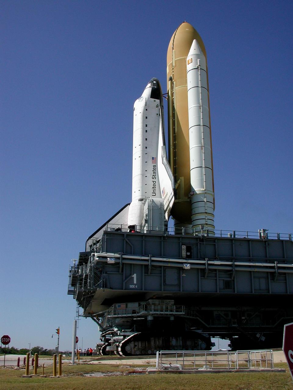 KENNEDY SPACE CENTER, FLA. -- Space Shuttle Endeavour and the Mobile Launcher Platform (MLP) start backing through the gate to Launch Pad 39B after a cracked cleat was discovered on the crawler-transporter. Workers near the pad (behind the crawler track) look at the cleats. The vehicle, which moves the MLP and Shuttle at about 1 mph, has a leveling system designed to keep the top of the Space Shuttle vertical while negotiating the 5 percent grade leading to the top of the pad. When the Shuttle-MLP are back on level ground, the crawler tracks will be inspected and the broken cleat repaired. Endeavour is scheduled to be launched Nov. 30 at 10:01 p.m. EST on mission STS-97, the sixth construction flight to the International Space Station. Its payload includes the P6 Integrated Truss Structure and a photovoltaic (PV) module, with giant solar arrays that will provide power to the Station. The mission includes two spacewalks to complete the solar array connections
