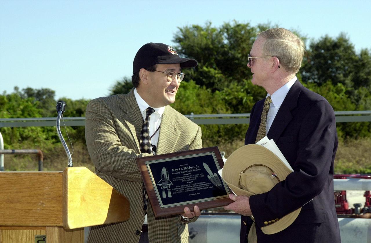 At the commissioning of a new high-pressure helium pipeline at Kennedy Space Center, Ramon Lugo, acting executive director, JPMO , presents a plaque to Center Director Roy Bridges. The pipeline will service launch needs at the new Delta IV Complex 37 at Cape Canaveral Air Force Station. Others at the ceremony were Jerry Jorgensen, pipeline project manager, Space Gateway Support (SGS); Col. Samuel Dick, representative of the 45th Space Wing; David Herst, director, Delta IV Launch Sites; Pierre Dufour, president and CEO, Air Liquide America Corporation; and Michael Butchko, president, SGS. The nine-mile-long buried pipeline will also serve as a backup helium resource for Shuttle launches. Nearly one launch’s worth of helium will be available in the pipeline to support a Shuttle pad in an emergency. The line originates at the Helium Facility on KSC and terminates in a meter station at the perimeter of the Delta IV launch pad