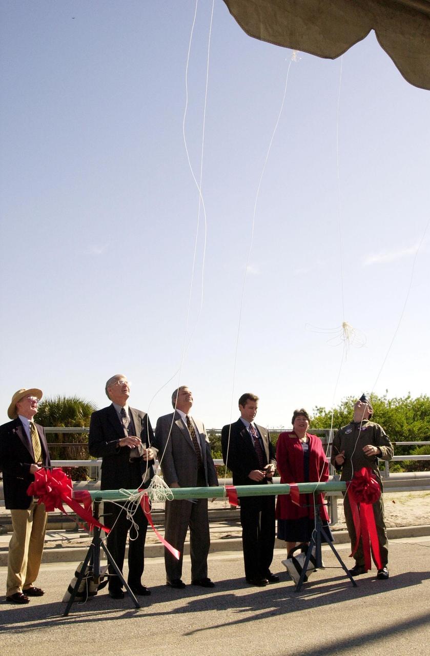 At the commissioning of a new high-pressure helium pipeline at Kennedy Space Center, participants watch as helium-filled balloons take to the sky after their lines were cut. From left, they are Center Director Roy Bridges; Michael Butchko, president, SGS; Pierre Dufour, president and CEO, Air Liquide America Corporation; David Herst, director, Delta IV Launch Sites; Pamela Gillespie, executive administrator, office of Congressman Dave Weldon; and Col. Samuel Dick, representative of the 45th Space Wing. The nine-mile-long buried pipeline will service launch needs at the new Delta IV Complex 37 at Cape Canaveral Air Force Station. It will also serve as a backup helium resource for Shuttle launches. Nearly one launch’s worth of helium will be available in the pipeline to support a Shuttle pad in an emergency. The line originates at the Helium Facility on KSC and terminates in a meter station at the perimeter of the Delta IV launch pad. Others at the ceremony were Jerry Jorgensen, pipeline project manager, Space Gateway Support (SGS), and Ramon Lugo, acting executive director, JPMO