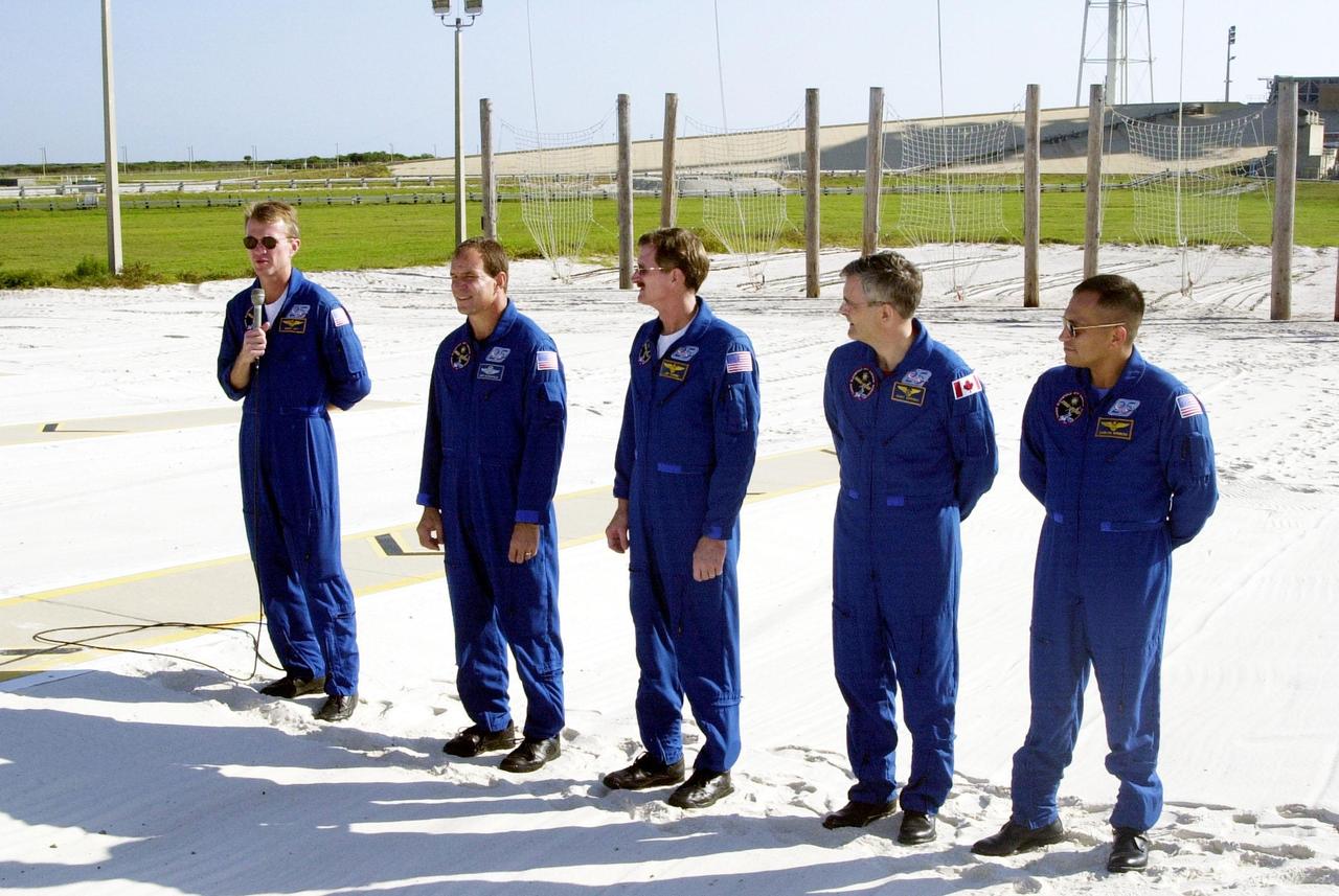KENNEDY SPACE CENTER, Fla. -- Standing in the slidewire landing zone at Launch Pad 39B, the STS-97 crew respond to questions from the media. They are, left to right, Commander Brent Jett, Pilot Mike Bloomfield and Mission Specialists Joe Tanner, Marc Garneau and Carlos Noriega. Garneau is with the Canadian Space Agency. The nets suspended behind them are a braking system catch net for the slidewire baskets that provide emergency exit from the orbiter and Fixed Service Structure. The crew is at KSC to take part in Terminal Countdown Demonstration Test activities that include emergency egress training, familiarization with the payload, and a simulated launch countdown. Visible in the background are the solid rocket booster and external tank on Space Shuttle Endeavour. Mission STS-97is the sixth construction flight to the International Space Station. Its payload includes the P6 Integrated Truss Structure and a photovoltaic (PV) module, with giant solar arrays that will provide power to the Station. The mission includes two spacewalks to complete the solar array connections. STS-97 is scheduled to launch Nov. 30 at about 10:05 p.m. EST