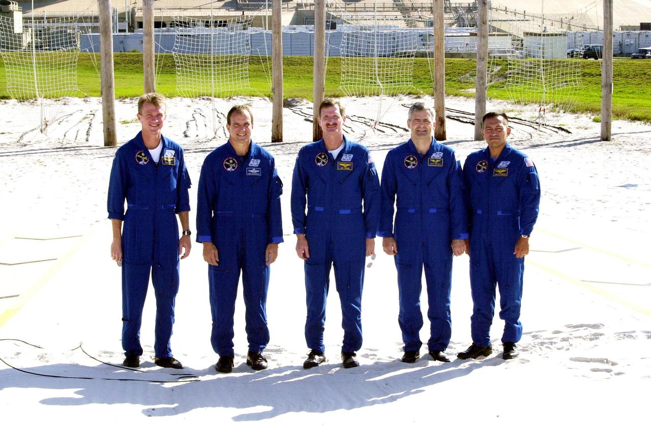 KENNEDY SPACE CENTER, Fla. -- The STS-97 crew poses for another photo after meeting with the media at the slidewire landing zone. They are, left to right, Commander Brent Jett, Pilot Mike Bloomfield and Mission Specialists Joe Tanner, Marc Garneau and Carlos Noriega. Garneau is with the Canadian Space Agency. The nets suspended behind them are a braking system catch net for the slidewire baskets that provide emergency exit from the orbiter and Fixed Service Structure. The crew is at KSC to take part in Terminal Countdown Demonstration Test activities that include emergency egress training, familiarization with the payload, and a simulated launch countdown. Visible in the background are the solid rocket booster and external tank on Space Shuttle Endeavour. Mission STS-97is the sixth construction flight to the International Space Station. Its payload includes the P6 Integrated Truss Structure and a photovoltaic (PV) module, with giant solar arrays that will provide power to the Station. The mission includes two spacewalks to complete the solar array connections. STS-97 is scheduled to launch Nov. 30 at 10:05 p.m. EST