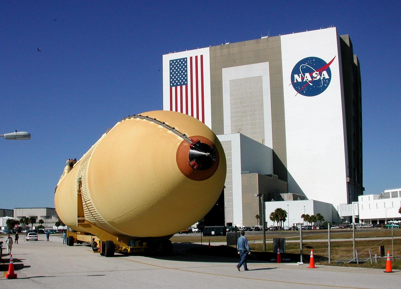 KENNEDY SPACE CENTER, FLA. -- A newly arrived external tank begins the turn on the road leading to the Vehicle Assembly Building (VAB), seen behind the tank. Seated in his perch near the rear left wheels is the transporter driver. The tank will be moved through the open door (facing the tank) into the main transfer aisle.; From there it will be moved to one of the high bays and await stacking for a future Shuttle mission.; External tanks are built by the NASA Michoud Assembly Facility in New Orleans and transported by barge to Cape Canaveral and then up the Banana River to the turn basin in the Launch Complex 39 Area