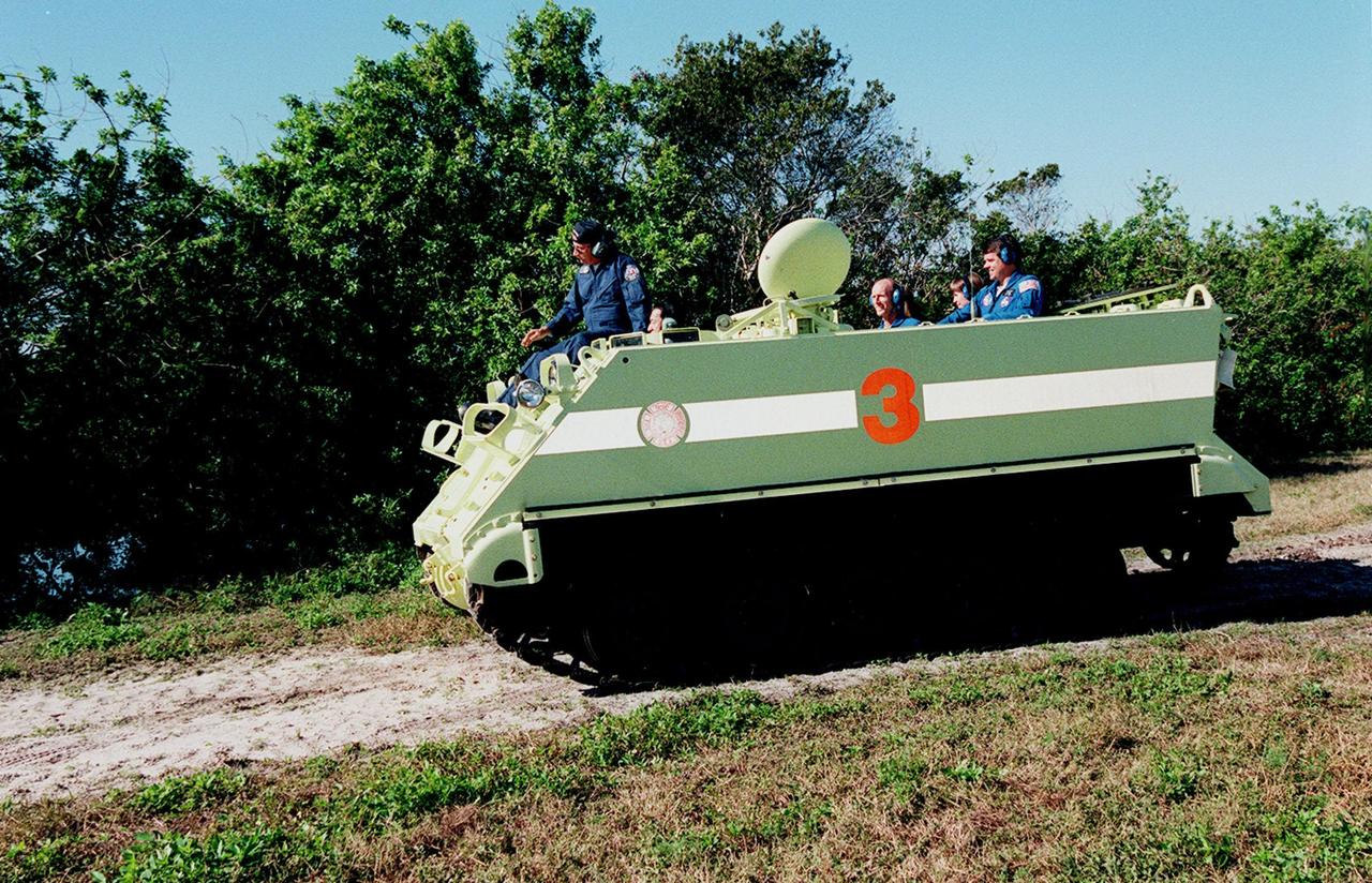 STS-99 Mission Specialist Mamoru Mohri, who is with the National Space Development Agency (NASDA) of Japan, practices driving an armored personnel carrier under the watchful eye of Capt. George Hoggard (riding on the front), trainer with the KSC Fire Department. The vehicle is part of emergency egress training during Terminal Countdown Demonstration Test (TCDT) activities and could be used by the crew in the event of an emergency at the pad during which the crew must make a quick exit from the area. Riding in the rear of the carrier are Mission Specialists Gerhard Thiele (center), Janice Voss (Ph.D.), and Commander Kevin Kregel. TCDT provides the crew with simulated countdown exercises, emergency egress training, and opportunities to inspect the mission payloads in the orbiter's payload bay. STS-99 is the Shuttle Radar Topography Mission, which will chart a new course, using two antennae and a 200-foot-long section of space station-derived mast protruding from the payload bay to produce unrivaled 3-D images of the Earth's surface. The result of the Shuttle Radar Topography Mission could be close to 1 trillion measurements of the Earth's topography. Besides contributing to the production of better maps, these measurements could lead to improved water drainage modeling, more realistic flight simulators, better locations for cell phone towers, and enhanced navigation safety. Launch of Endeavour on the 11-day mission is scheduled for Jan. 31 at 12:47 p.m. EST