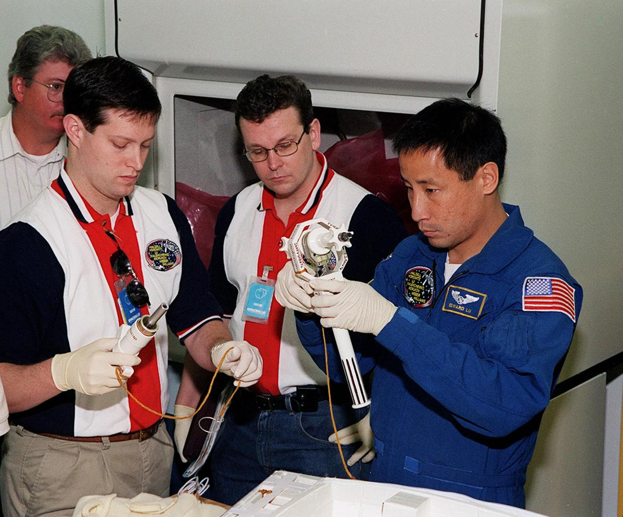 KENNEDY SPACE CENTER, FLA. -- At SPACEHAB, in Cape Canaveral, technicians help STS-101 Mission Specialist Edward Tsang Lu become familiar with equipment for the mission. Lu and other members of the crew are taking part in a Crew Equipment Interface Test, which gives them an opportunity to look over equipment and payloads that will fly on the mission. Space Shuttle Atlantis will be carrying the SPACEHAB Double Module, which carries internal logistics and resupply cargo for station outfitting. Launch of Atlantis on mission STS-101 is scheduled no earlier than April 13, 2000