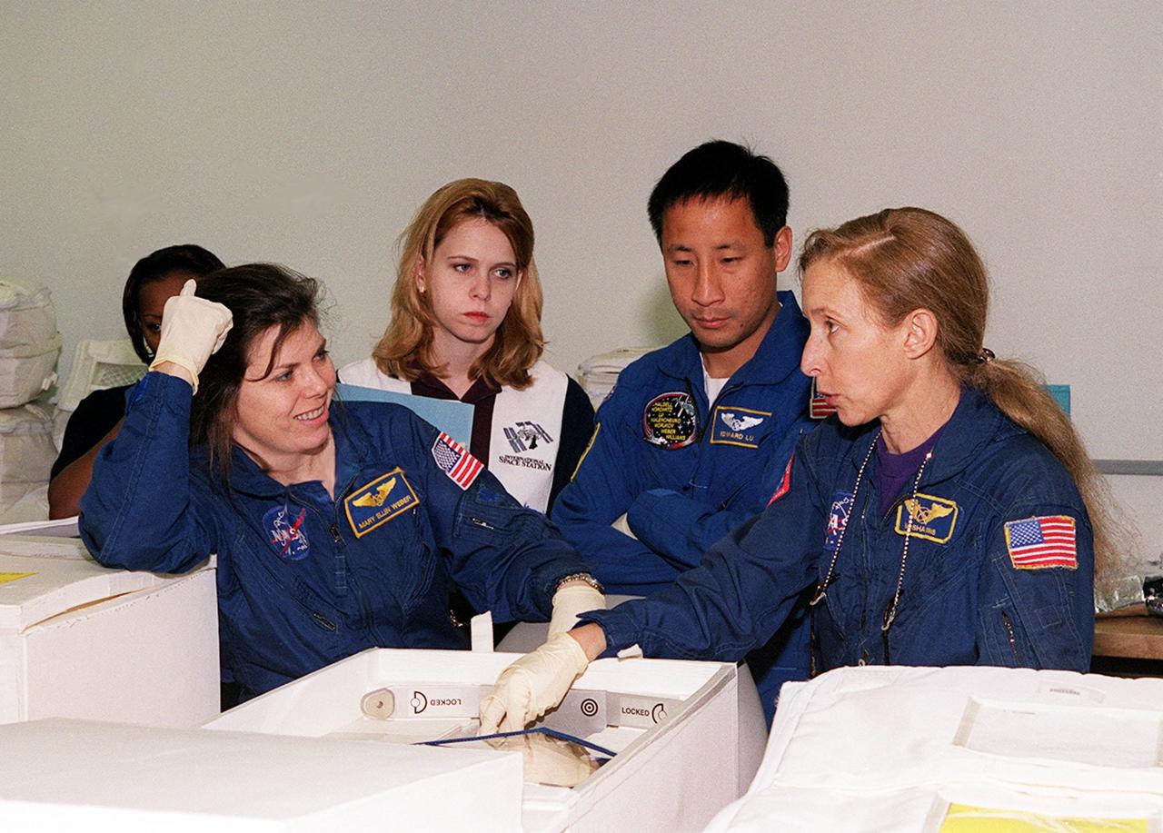 KENNEDY SPACE CENTER, FLA. -- With technicians looking on at SPACEHAB, in Cape Canaveral, members of the STS-101 crew take part in a Crew Equipment Interface Test, which gives them an opportunity to look over equipment and payloads that will fly on the mission. In the foreground at left is Mission Specialist Mary Ellen Weber (Ph.D.), at center is Mission Specialist Edward Tsang Lu; at right is astronaut Marsha Ivins, who is assigned to mission STS-98 and is a veteran of five space flights. Her last flight, STS-81, including docking with the Russian Mir, and carrying the SPACEHAB double module to transfer tons of food and other cargo. On mission STS-101, Space Shuttle Atlantis will also be carrying the SPACEHAB Double Module, which will carry internal logistics and resupply cargo for station outfitting. Launch of Atlantis is scheduled no earlier than April 13, 2000