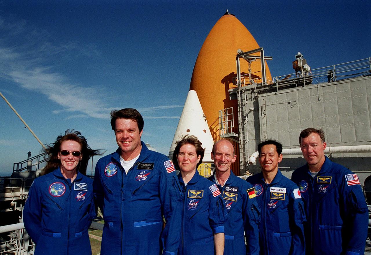 KENNEDY SPACE CENTER, Fla. --  At the 167-foot level of the Fixed Service Structure on Launch Pad 39A, the STS-99 crew pose for a photograph during Terminal Countdown Demonstration Test (TCDT) activities. Standing left to right are Mission Specialist Janet Lynn Kavandi (Ph.D.), Commander Kevin Kregel, Mission Specialists Janice Voss (Ph.D.), Gerhard Thiele and Mamoru Mohri, and Pilot Dominic Gorie. Thiele is with the European Space Agency and Mohri is with the National Space Development Agency (NASDA) of Japan. Behind them are visible the top of a solid rocket booster (white) and external tank (orange). The TCDT provides the crew with simulated countdown exercises, emergency egress training, and opportunities to inspect the mission payloads in the orbiter's payload bay. STS-99 is the Shuttle Radar Topography Mission, which will chart a new course, using two antennae and a 200-foot-long section of space station-derived mast protruding from the payload bay to produce unrivaled 3-D images of the Earth's surface. The result of the Shuttle Radar Topography Mission could be close to 1 trillion measurements of the Earth's topography. Besides contributing to the production of better maps, these measurements could lead to improved water drainage modeling, more realistic flight simulators, better locations for cell phone towers, and enhanced navigation safety. Launch of Endeavour on the 11-day mission is scheduled for Jan. 31 at 12:47 p.m. EST