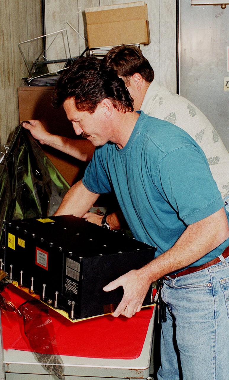 KENNEDY SPACE CENTER, FLA. -- Workers in a Quality trailer in the Launch Pad 39B Area unwrap a new Enhanced Main Events Controller (E-MEC) to be installed in Shuttle Endeavour. The original E-MEC in Endeavour became suspect during the Jan. 31 launch countdown and mission STS-99 was delayed when NASA managers decided to replace it. Each Shuttle carries two enhanced master events controllers (E-MECs), which provide relays for onboard flight computers to send signals to arm and fire pyrotechnics that separate the solid rockets and external tank during assent. The E-MECs are located in the orbiter's aft compartment and both are needed for the Shuttle to be cleared for flight. Currently Endeavour and Columbia are the only two orbiters with the E-MECs. Built by Rockwell's Satellite Space Electronics Division, Anaheim, Calif., each unit weighs 65 pounds and is approximately 20 inches long, 13 inches wide and 8 inches tall. Previously, three Shuttle flights have been scrubbed or delayed due to faulty MECs: STS-73, STS-49 and STS-41-D. Before workers can begin E-MEC replacement efforts at the launch pad, cryogenic reactants must be offloaded from the orbiter and Space Shuttle ordnance disconnected. The next scheduled date for launch of STS-99 is Feb. 11 at 12:30 p.m. EST