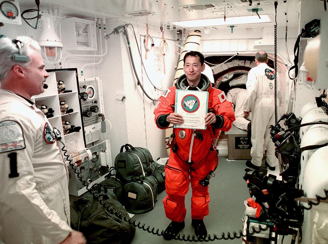 STS-99 Mission Specialist Mamoru Mohri of Japan holds a memento from friends before entering orbiter Endeavour. With him are members of the White Room closeout crew, Chris Meinert (left), closeout chief, and Jack Burritt (background), Quality Assurance specialist. The White Room is an environmental chamber at the end of the orbiter access arm, on the fixed service structure, that provides entry to the orbiter crew compartment. STS-99, known as the Shuttle Radar Topography Mission (SRTM), will chart a new course to produce unrivaled 3-D images of the Earth's surface. The result of the Shuttle Radar Topography Mission could be close to 1 trillion measurements of the Earth's topography. Scheduled for liftoff at 12:30 p.m. EST, the mission is expected to last 11days, with Endeavour landing at KSC Tuesday, Feb. 22, at 4:36 p.m. EST. This is the 97th Shuttle flight and 14th for Shuttle Endeavour