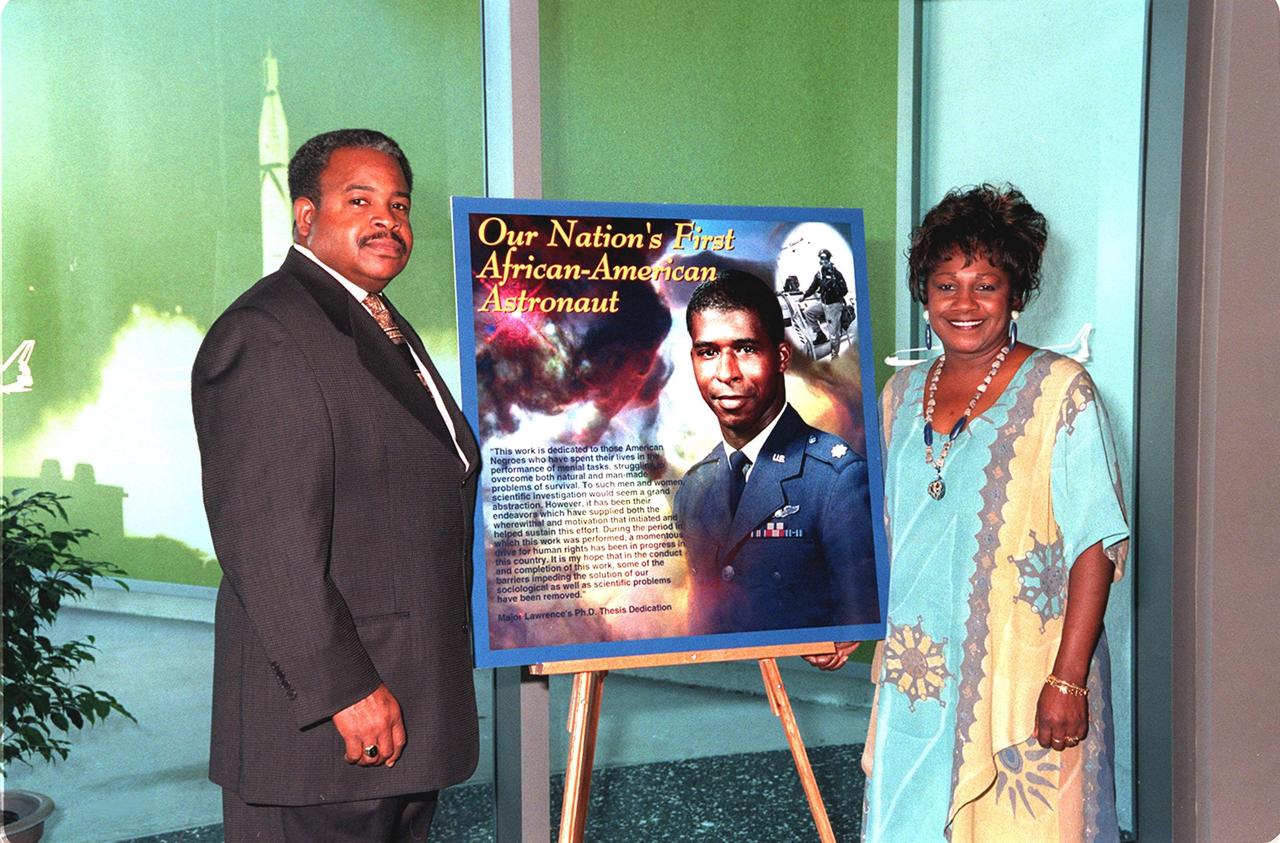 Mack McKinney (left), chief, Programs Resources Management, and Delores Abraham (right), with the Astronaut office, flank one of the posters decorating the Early Space Exploration Conference Center at the KSC Visitor Complex for the 2000 African American History Month Celebration Luncheon. McKinney is chairperson for the event