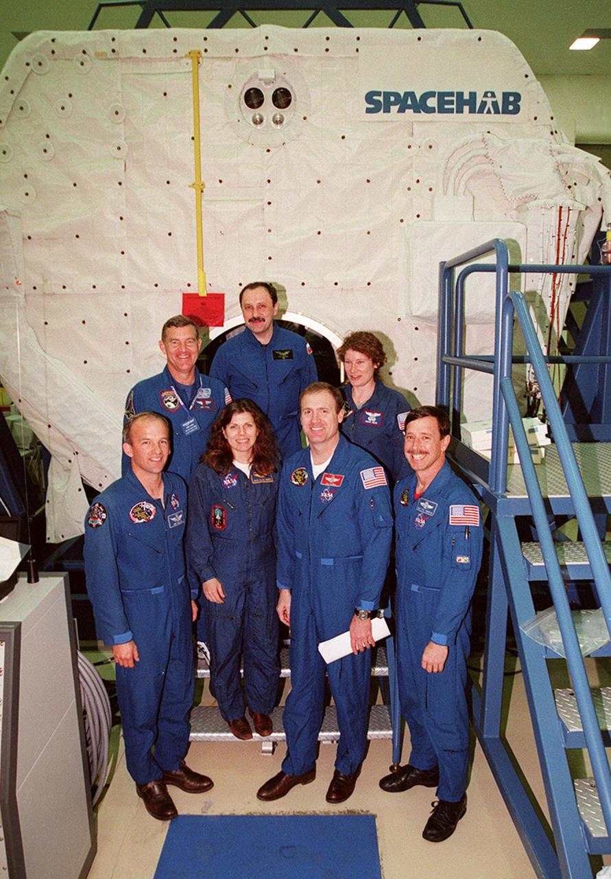 KENNEDY SPACE CENTER, FLA. -- The newly formed crew of STS-101 pose in front of the Spacehab double module in the Space Station Processing Facility. In the foreground from left are Mission Specialists Jeffrey Williams and Mary Ellen Weber, Commander James Halsell and Pilot Scott Horowitz; in the back are Mission Specialists James Voss, Yuri Usachev of Russia and Susan Helms. The crew will be responsible for preparing the International Space Station for the arrival of the Zvezda Service Module, expected to be launched by Russia in July 2000. Also, the crew will conduct one space walk to perform maintenance on the Space Station and deliver logistics and supplies. This will be the third assembly flight for the Space Station. STS-101 is scheduled to launch no earlier than April 13 from Launch Pad 39A