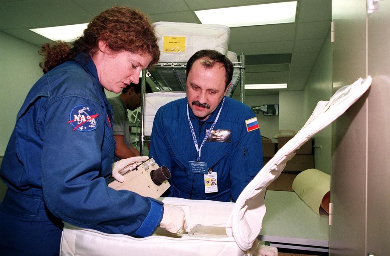 KENNEDY SPACE CENTER, FLA. -- As part of Crew Equipment Interface Test (CEIT) activities at SPACEHAB, in Cape Canaveral, Fla., STS-101 Mission Specialists Susan Helms and Yuri Usachev of Russia look over some of the equipment for their mission to the International Space Station. Other members of the crew taking part in the CEIT are Commander James Halsell, Pilot Scott Horowitz, and Mission Specialists Mary Ellen Weber, James Voss, and Jeffrey Williams. The STS-101 crew will be responsible for preparing the Space Station for the arrival of the Zvezda Service Module, expected to be launched by Russia in July 2000. Also, the crew will conduct one space walk to perform maintenance on the Space Station and deliver logistics and supplies. This will be the third assembly flight for the Space Station. STS-101 is scheduled to launch no earlier than April 13 from Launch Pad 39A