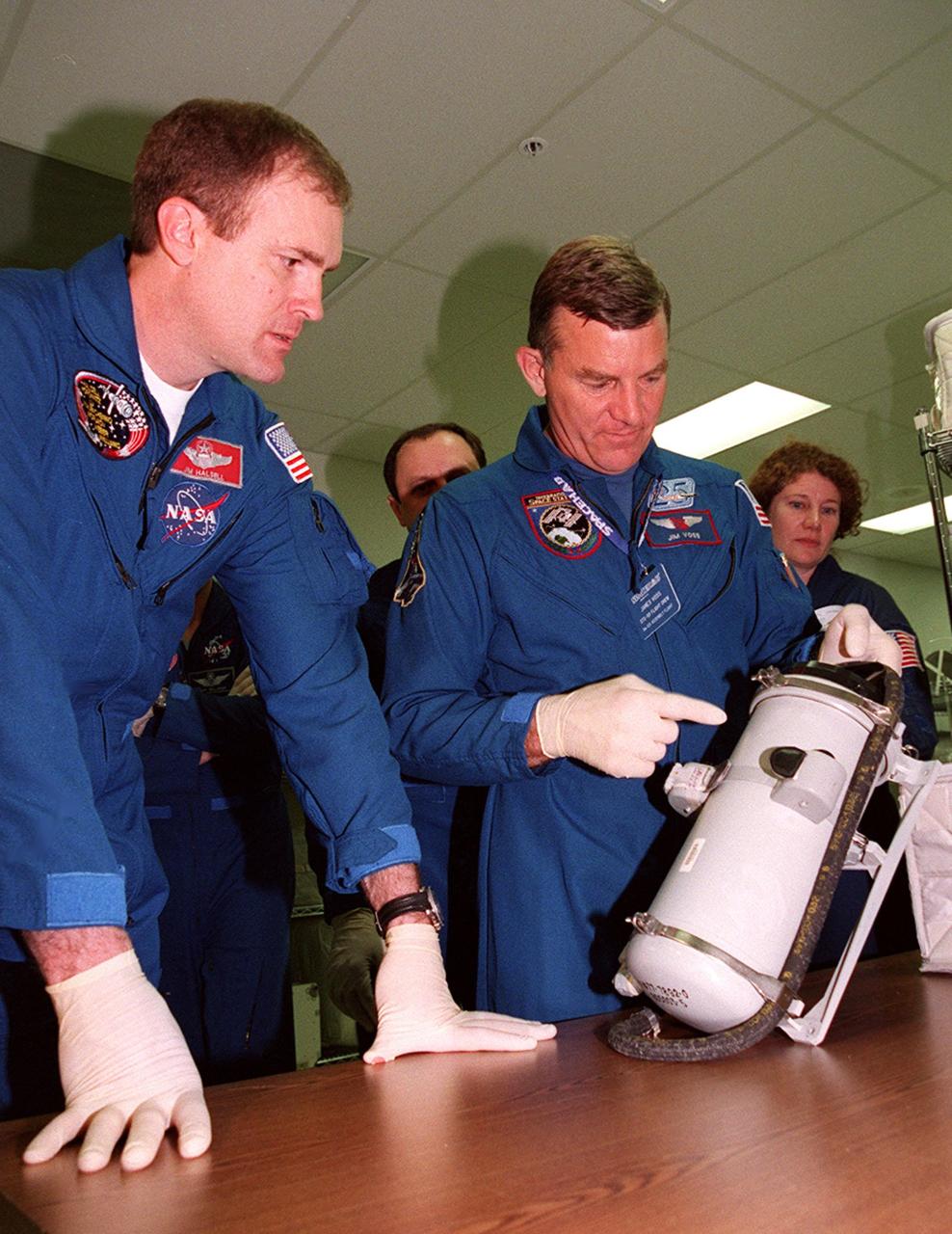 KENNEDY SPACE CENTER, FLA. -- As part of Crew Equipment Interface Test (CEIT) activities at SPACEHAB, in Cape Canaveral, Fla., STS-101 Commander James Halsell (left) and Mission Specialist James Voss (right) look over a piece of equipment for their mission to the International Space Station. Behnd them are Mission Specialists Yuri Usachev and Susan Helms. Other members of the crew taking part in the CEIT are Pilot Scott Horowitz, and Mission Specialists Mary Ellen Weber and Jeffrey Williams. The STS-101 crew will be responsible for preparing the Space Station for the arrival of the Zvezda Service Module, expected to be launched by Russia in July 2000. Also, the crew will conduct one space walk to perform maintenance on the Space Station and deliver logistics and supplies. This will be the third assembly flight for the Space Station. STS-101 is scheduled to launch no earlier than April 13 from Launch Pad 39A
