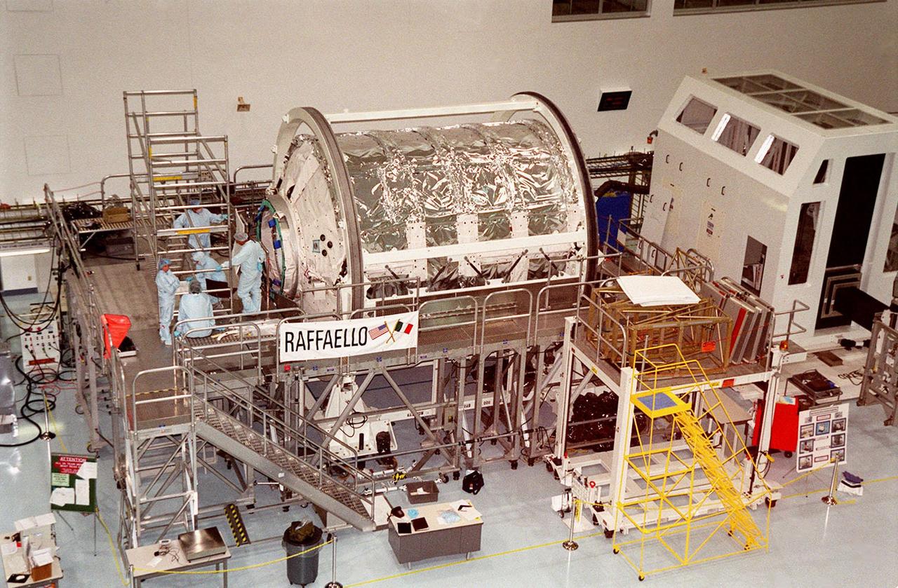 KENNEDY SPACE CENTER, FLA. -- Workers in the Space Station Processing Facility stand outside the Multi-Purpose Logistics Module Raffaello. One of Italy's major contribution to the International Space Station program, Raffaello is a reusable logistics carrier to resupply and return Space Station cargo requiring a pressurized environment. It is slated as a payload on mission STS-100. A date has not yet been determined for the mission