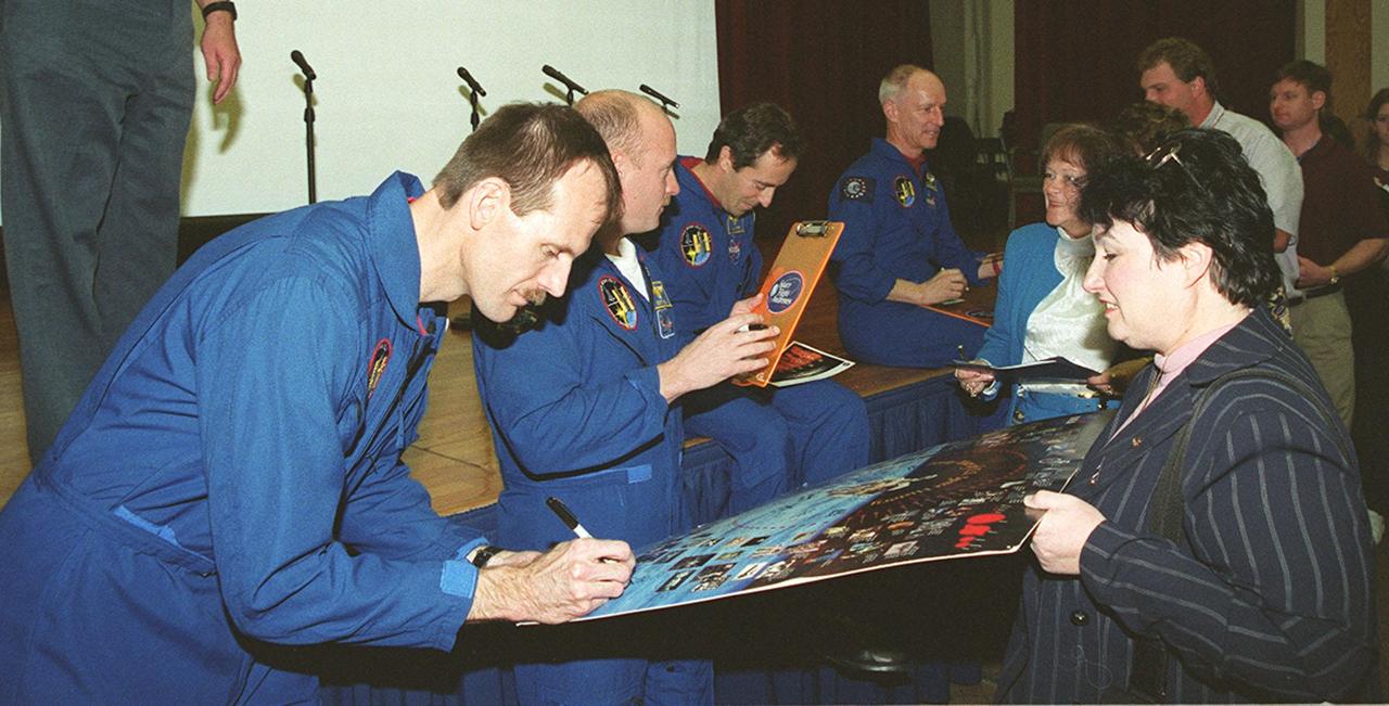 After a presentation at KSC for employees and VIPs about their mission, STS-103 crew members sign autographs. From left are Mission Specialist Steven Smith, Pilot Scott Kelly, and Mission Specialists Jean-Francois Clervoy and Claude Nicollier. The STS-103 mission, servicing the Hubble Space Telescope, included three space walks. STS-103 launched Dec. 19, 1999, and landed Dec. 27, 1999