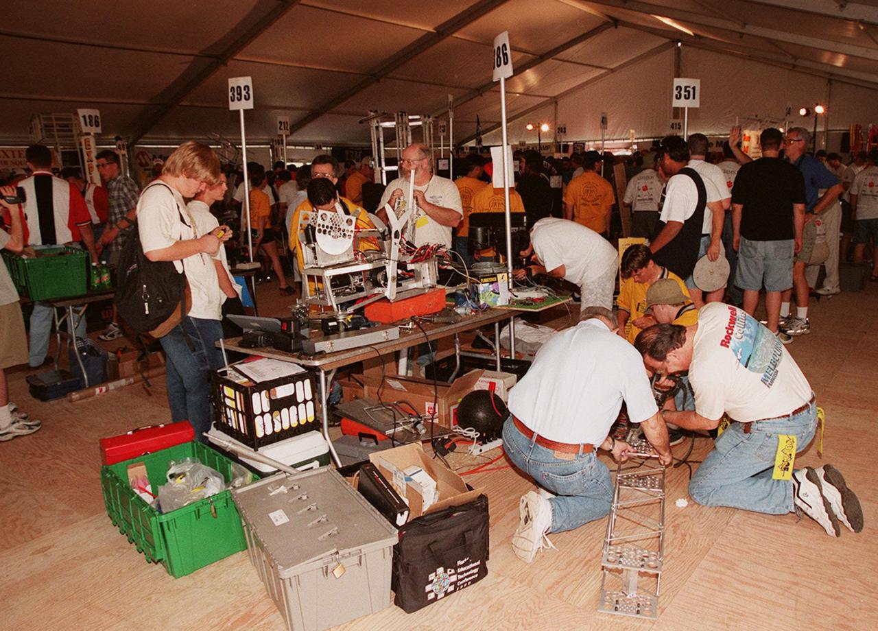 Team 393 from Morristown, Ind., sets up its robot on a table to prepare it for the FIRST (For Inspiration and Recognition of Science and Technology) Southeast Regional competition March 9-11 at the KSC Visitor Complex. KSC is co-sponsoring the team, The Bee Bots, from Morristown Junior and Senior High Schools. On the floor at right is team 386, known as Voltage: The South Brevard First Team. This team is made up of students from Eau Gallie, Satellite, Palm Bay, Melbourne, Bayside and Melbourne Central Catholic High Schools. They are sponsored by KSC as well as Harris Corp., Intersil Corp., Interface & Control Systems. Inc. and Rockwell Collins. Teams of high school students are testing the limits of their imagination using robots they have designed, with the support of business and engineering professionals and corporate sponsors, to compete in a technological battle against other schools' robots. Of the 30 high school teams competing at KSC, 16 are Florida teams co-sponsored by NASA and KSC contractors. Local high schools participating are Astronaut, Bayside, Cocoa Beach, Eau Gallie, Melbourne, Melbourne Central Catholic, Palm Bay, Rockledge, Satellite, and Titusville