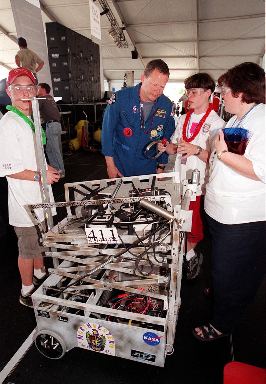 Astronaut David Brown looks over the robot named "L'il Max" with members of the team The Bot Kickers! from Northwestern High School, Rock Hill, S.C. Students from all over the country are at the KSC Visitor Complex for the FIRST (For Inspiration and Recognition of Science and Technology) Southeast Regional competition being held March 9-11 in the Rocket Garden. Teams of high school students are testing the limits of their imagination using robots they have designed, with the support of business and engineering professionals and corporate sponsors, to compete in a technological battle against other schools' robots. Of the 30 high school teams competing, 16 are Florida teams co-sponsored by NASA and KSC contractors. Local high schools participating are Astronaut, Bayside, Cocoa Beach, Eau Gallie, Melbourne, Melbourne Central Catholic, Palm Bay, Rockledge, Satellite, and Titusville
