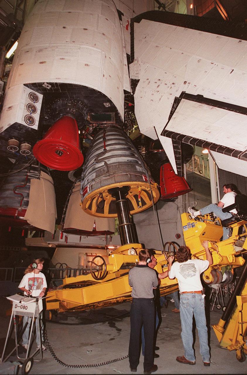 KENNEDY SPACE CENTER, FLA. -- Workers in the Vehicle Assembly Building oversee the replacement of Main Engine No. 1 in Space Shuttle Atlantis (overhead). An inventory review concerning defective main engine fuel pump tip seals indicated that defective seals might be present on the previous fuel pump for the engine. The decision was made to replace the suspect engine with one originally slated for Discovery. The main engine nozzle, visible in the photo, is 7.8 feet across and 9.4 feet high. Space Shuttle Atlantis is scheduled to launch no earlier than April 17, 2000, on mission STS-101 to resupply the International Space Station for the arrival of the next pressurized module, the Russian-built Zvezda