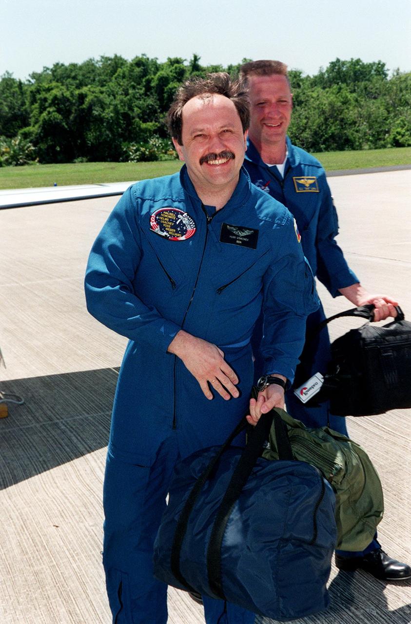 KENNEDY SPACE CENTER, FLA. -- STS-101 Mission Specialist Yury Usachev crosses the tarmac at KSC's Shuttle Landing Facility after arriving aboard a T-38 jet aircraft piloted by astronaut Gus Loria (behind). Usachev and the the rest of the crew are at KSC to take part in Terminal Countdown Demonstration Test (TCDT) activities that include emergency egress training and a dress rehearsal for launch. The other crew members are Commander James Halsell, Pilot Scott Horowitz, and Mission Specialists Mary Ellen Weber, James Voss, and Jeffrey Williams. During their mission to the International Space Station, the STS-101 crew will be delivering logistics and supplies, plus preparing the Station for the arrival of the Zvezda Service Module, expected to be launched by Russia in July 2000. Also, the crew will conduct one space walk to perform maintenance on the Space Station. This will be the third assembly flight for the Space Station. STS-101 is scheduled to launch April 24 at 4:15 p.m. from Launch Pad 39A