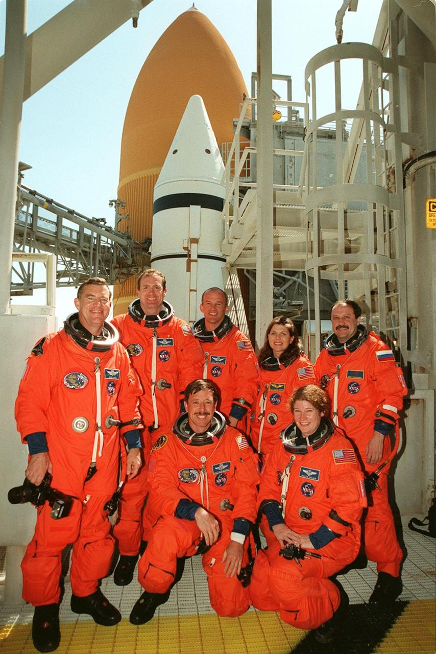 KENNEDY SPACE CENTER, FLA. -- During a break in Terminal Countdown Demonstration (TCDT) activities, the STS-101 crew poses for a photo at Launch Pad 39A. They are at the 195-foot level of the Fixed Service Structure for emergency egress training. Standing, from left to right, are Mission Specialist James Voss, Commander James D. Halsell Jr., and Mission Specialists Jeffrey N. Williams, Mary Ellen Weber and Yury Usachev of Russia. Kneeling in front are Pilot Scott J. "Doc" Horowitz and Mission Specialist Susan J. Helms. Behind them are the white solid rocket booster and orange external tank attached to Space Shuttle Atlantis. The TCDT also includes a simulated launch countdown and familiarization with the payload. During their mission to the International Space Station, the STS-101 crew will be delivering logistics and supplies, plus preparing the Station for the arrival of the Zvezda Service Module, expected to be launched by Russia in July 2000. Also, the crew will conduct one space walk to perform maintenance on the Space Station. This will be the third assembly flight for the Space Station. STS-101 is scheduled to launch April 24 at 4:15 p.m. from Launch Pad 39A