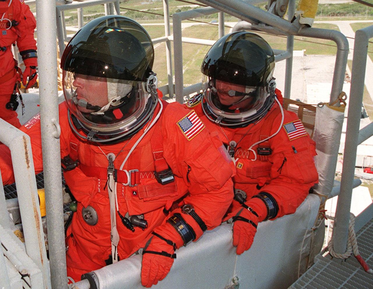 KENNEDY SPACE CENTER, FLA. -- Seated in a slidewire basket at the 195-foot level of the Fixed Service Structure, Launch Pad 39A, are (left to right) STS-101 Commander James D. Halsell Jr. and Pilot Scott J. "Doc" Horowitz. Halsell is reaching to pull the release lever that will send the basket shooting down the 1,200-foot slidewire to a bunker west of the launch pad. The crew is practicing emergency egress from the orbiter as part of Terminal Countdown Demonstration (TCDT) activities that include a simulated launch countdown and familiarization with the payload. During their mission to the International Space Station, the STS-101 crew will be delivering logistics and supplies, plus preparing the Station for the arrival of the Zvezda Service Module, expected to be launched by Russia in July 2000. Also, the crew will conduct one space walk to perform maintenance on the Space Station. This will be the third assembly flight to the Space Station. STS-101 is scheduled to launch April 24 at 4:15 p.m. from Launch Pad 39A